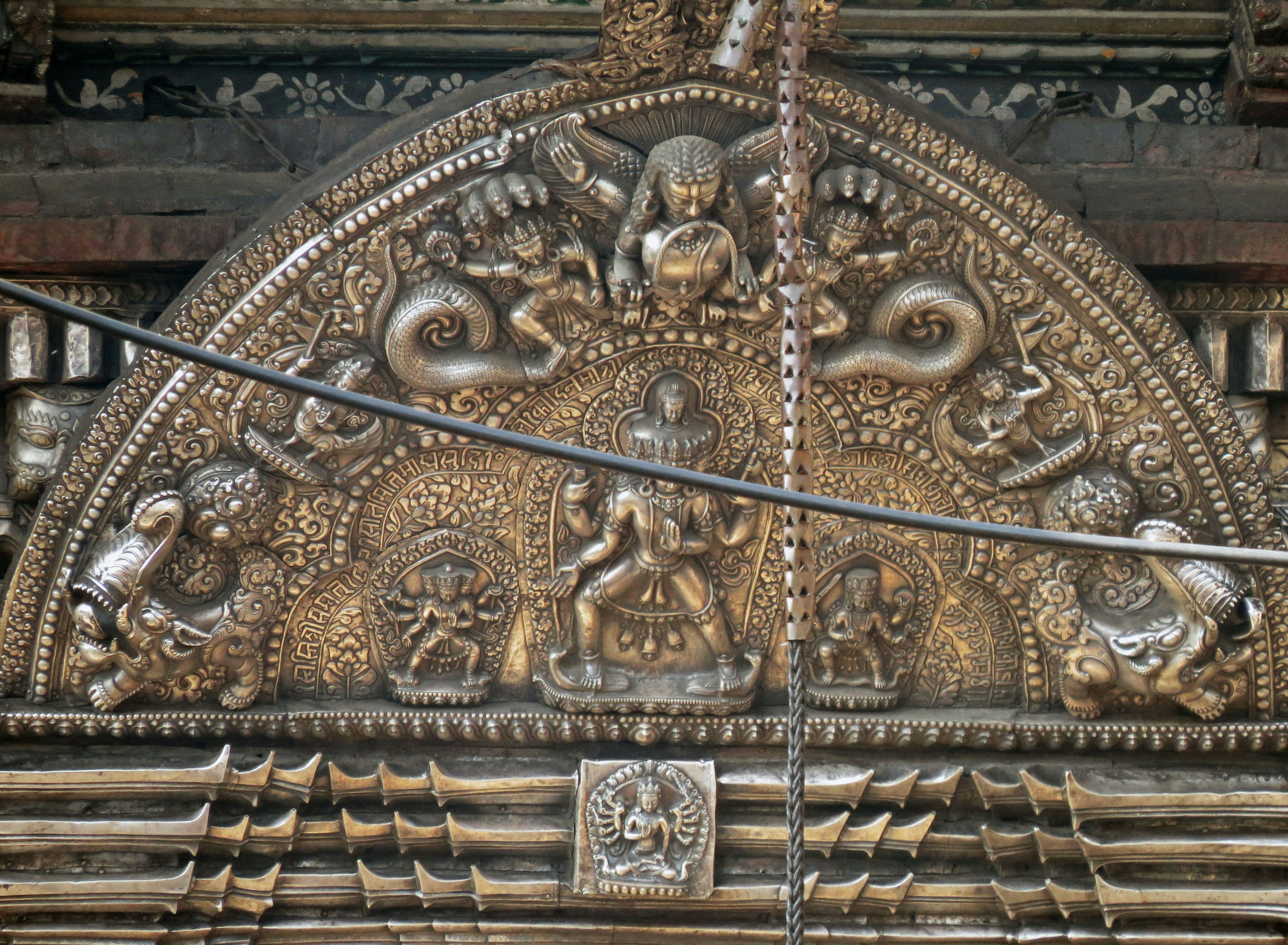 Escultura dorada decorativa en la parte superior de la entrada de un templo con diseños intrincados