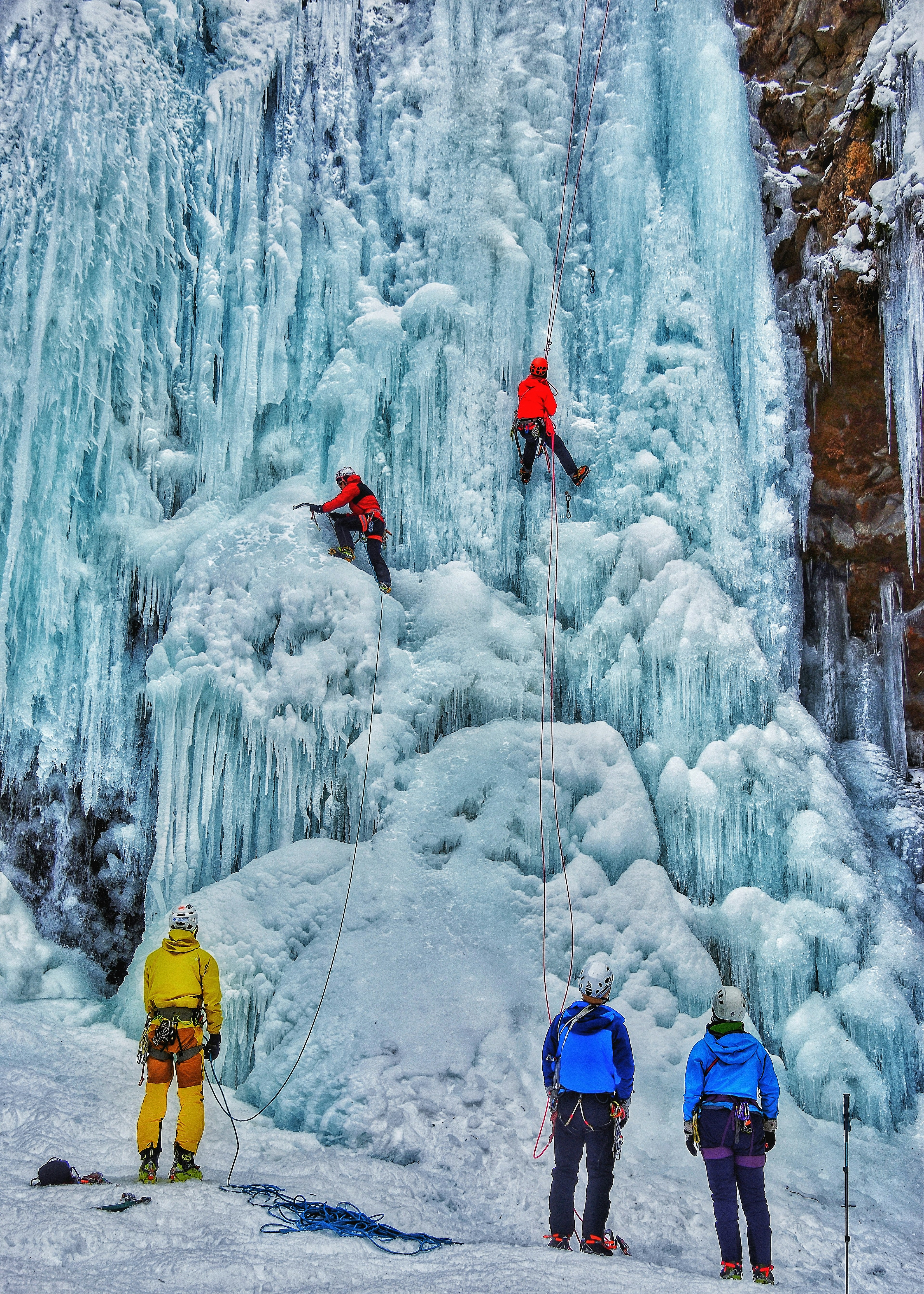 Grimpeurs de glace grimpant une cascade gelée avec des spectateurs en bas