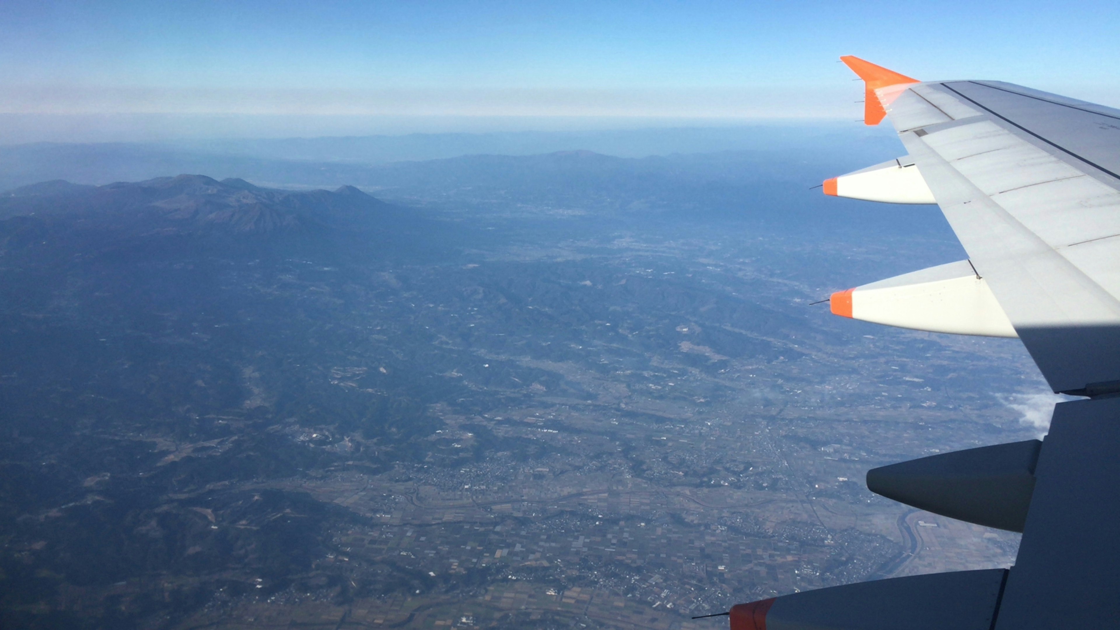 飛行機の翼から見える山々と都市の景色