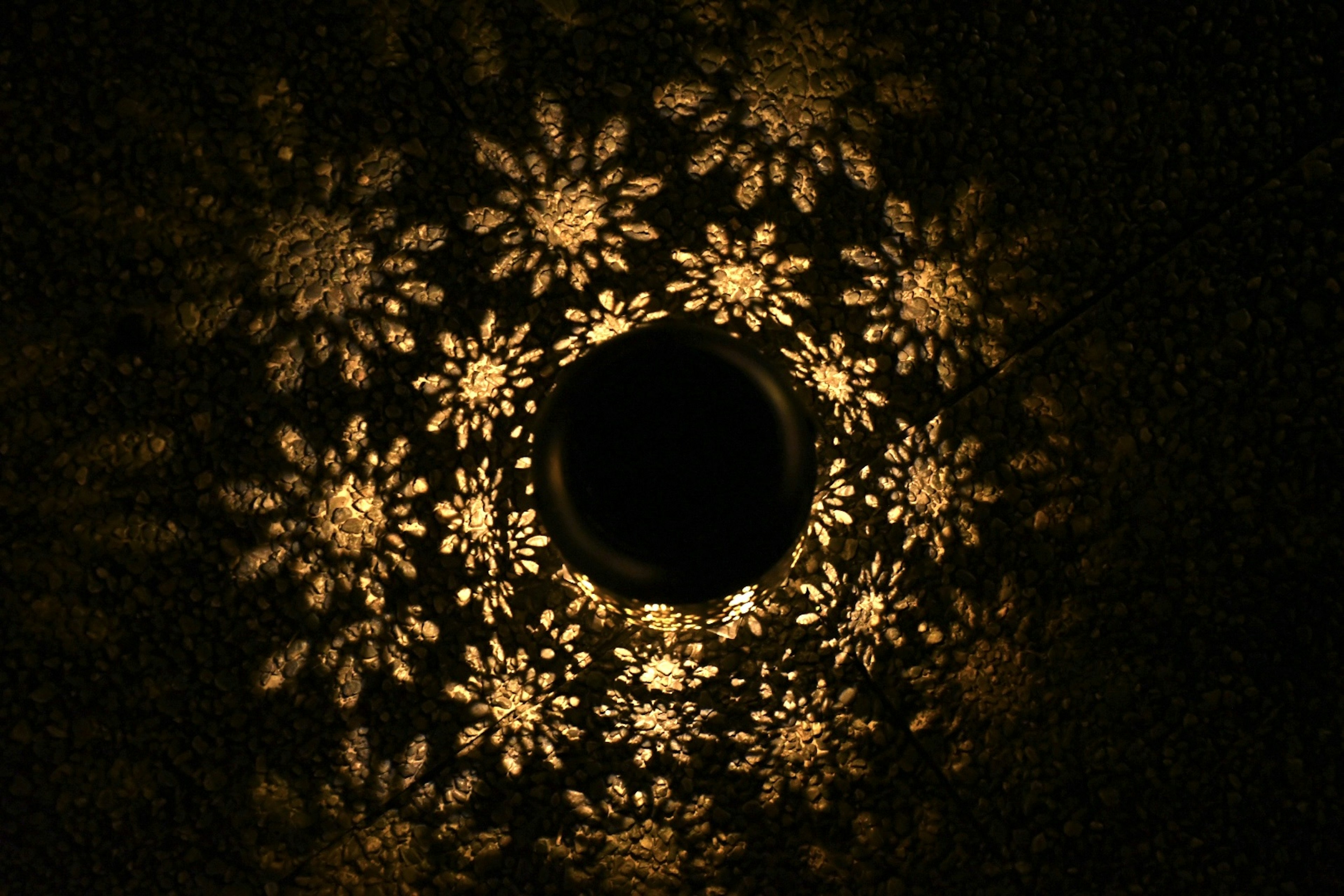 Image featuring floral light patterns radiating from a central hole against a dark background