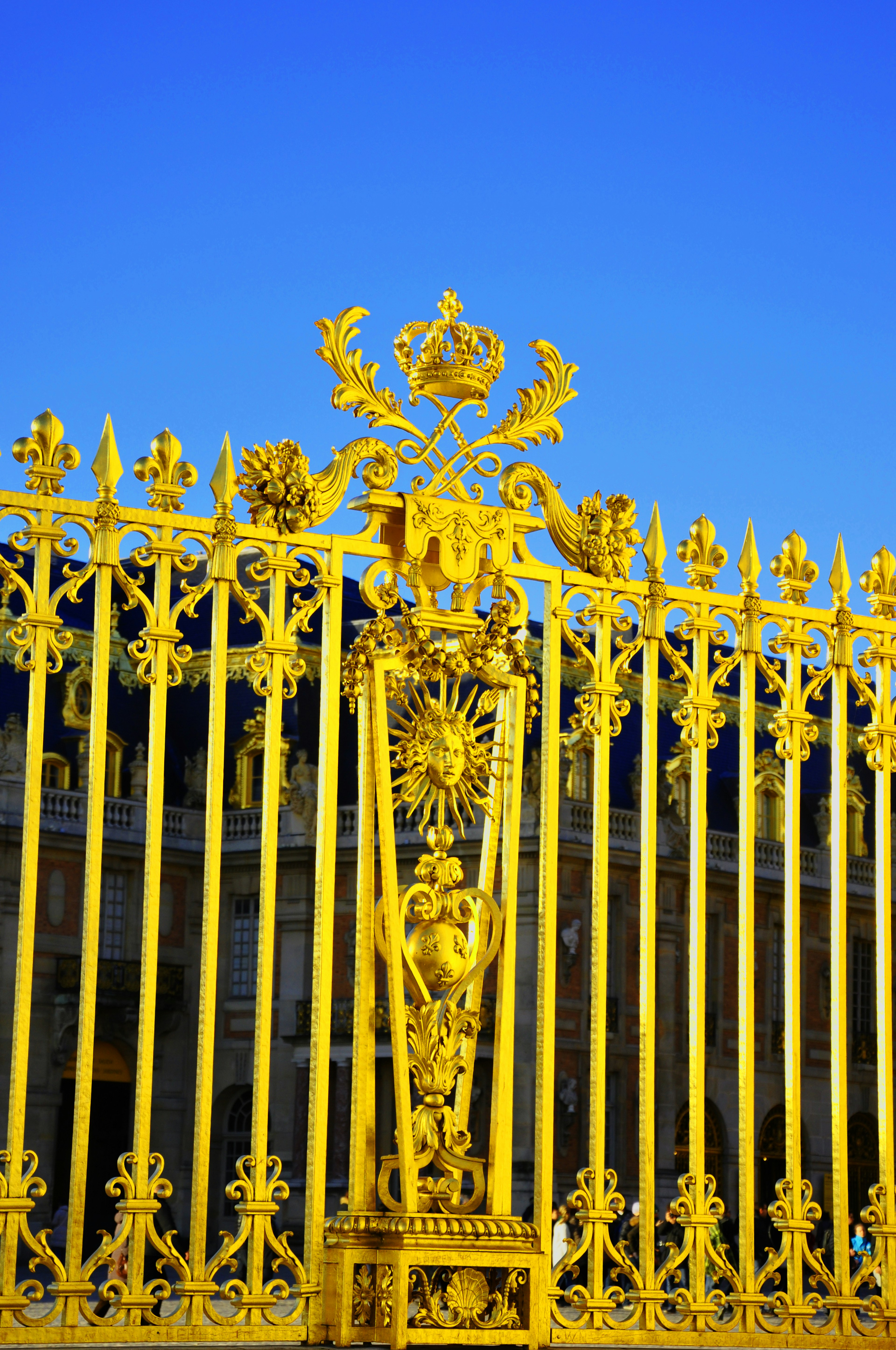 Puerta de hierro forjado dorada decorada contra un cielo azul claro