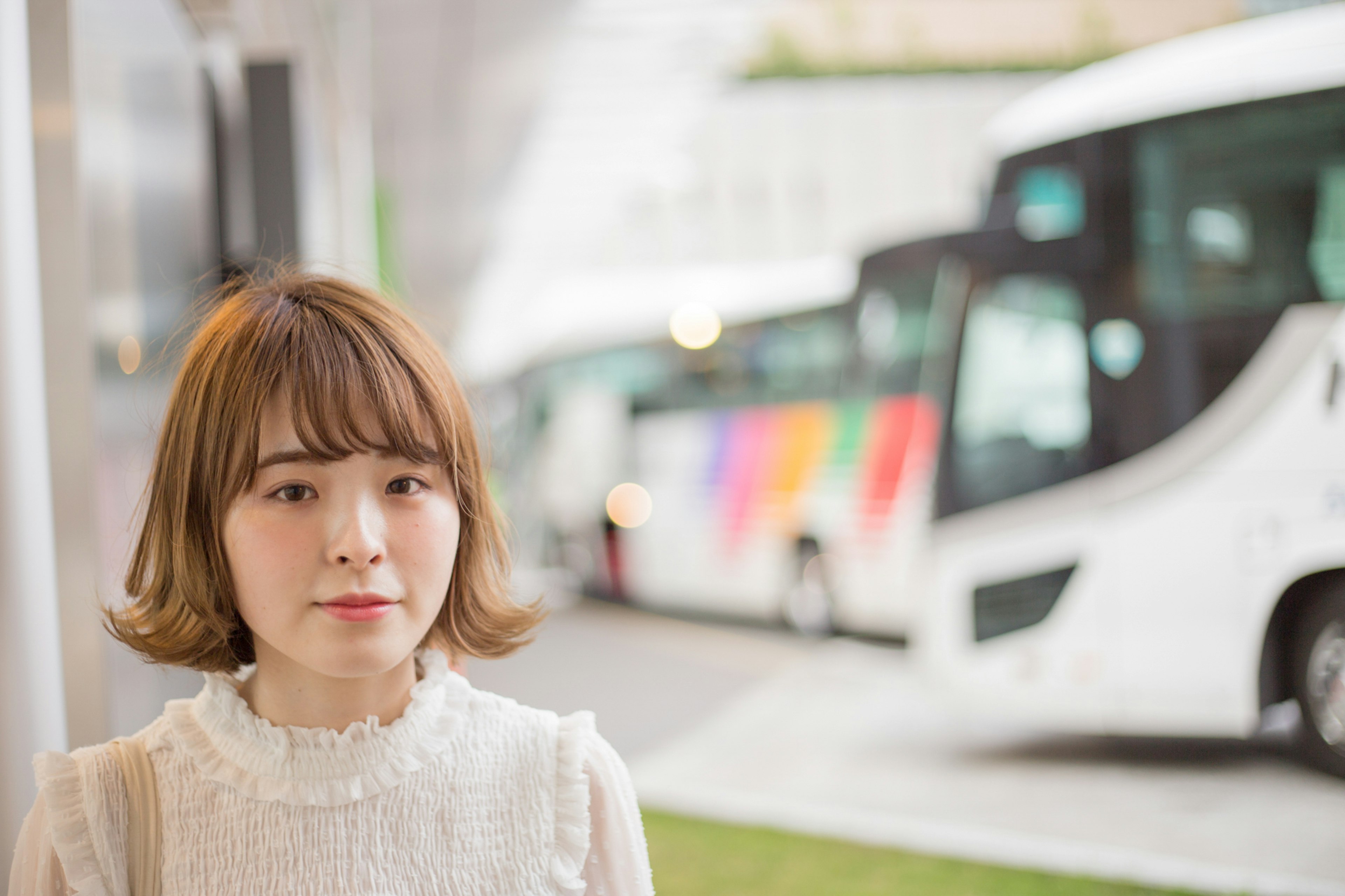 Una donna in piedi davanti a degli autobus Indossa una blusa bianca Gli autobus hanno design colorati