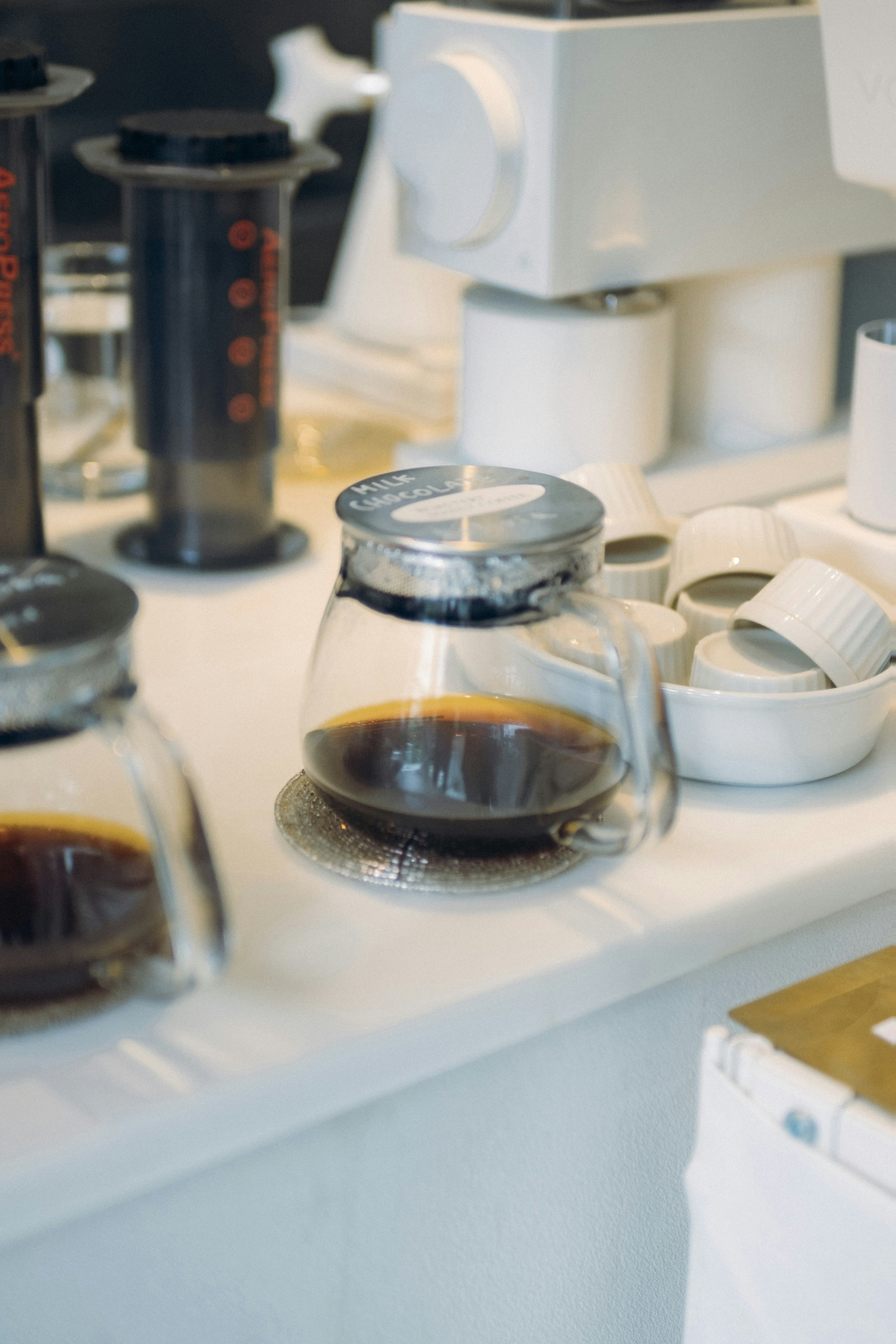 Une cafetière en verre avec du café et des tasses blanches sur un comptoir de café