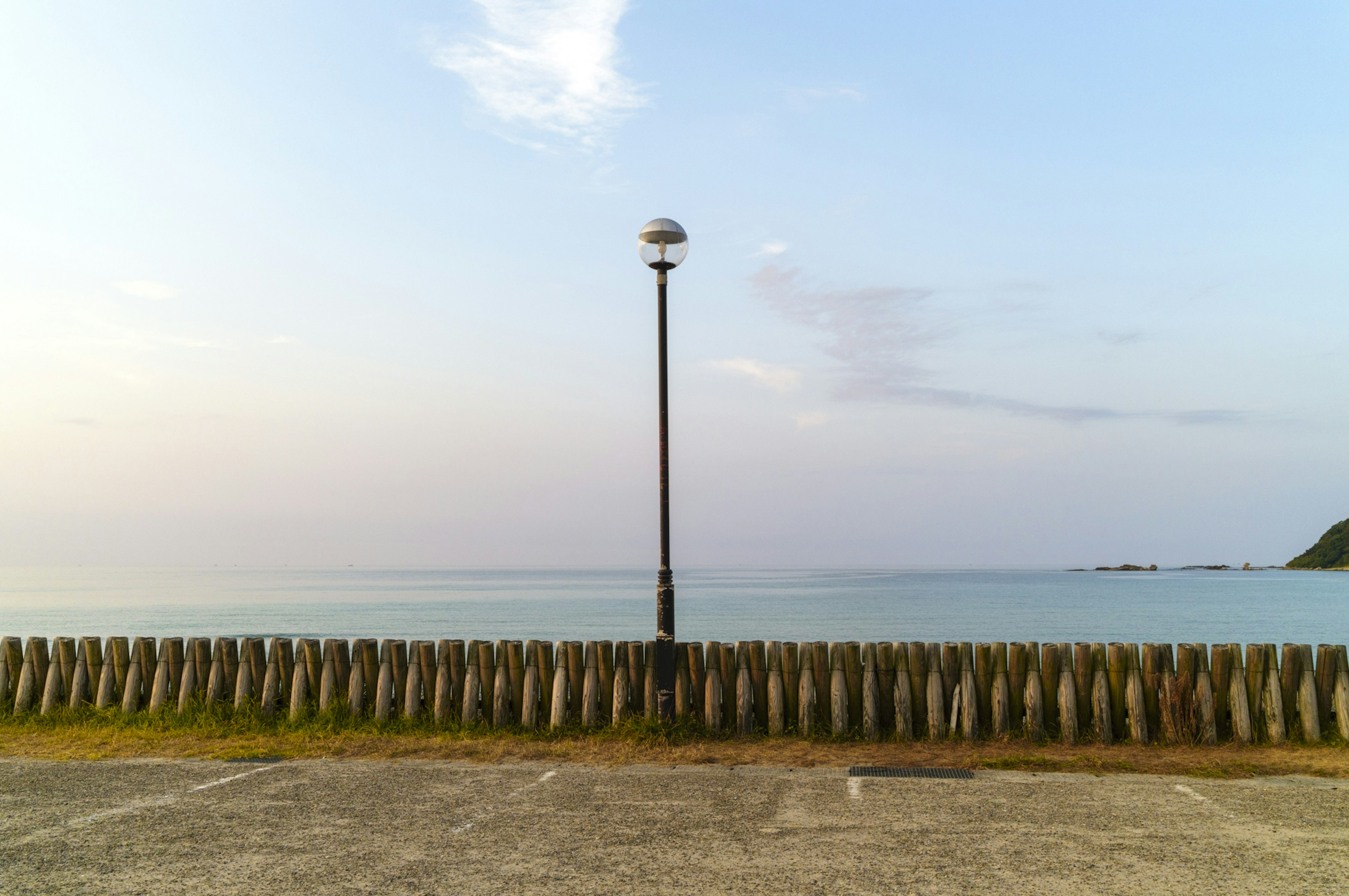 Serene seaside view with a lamp post and wooden barrier