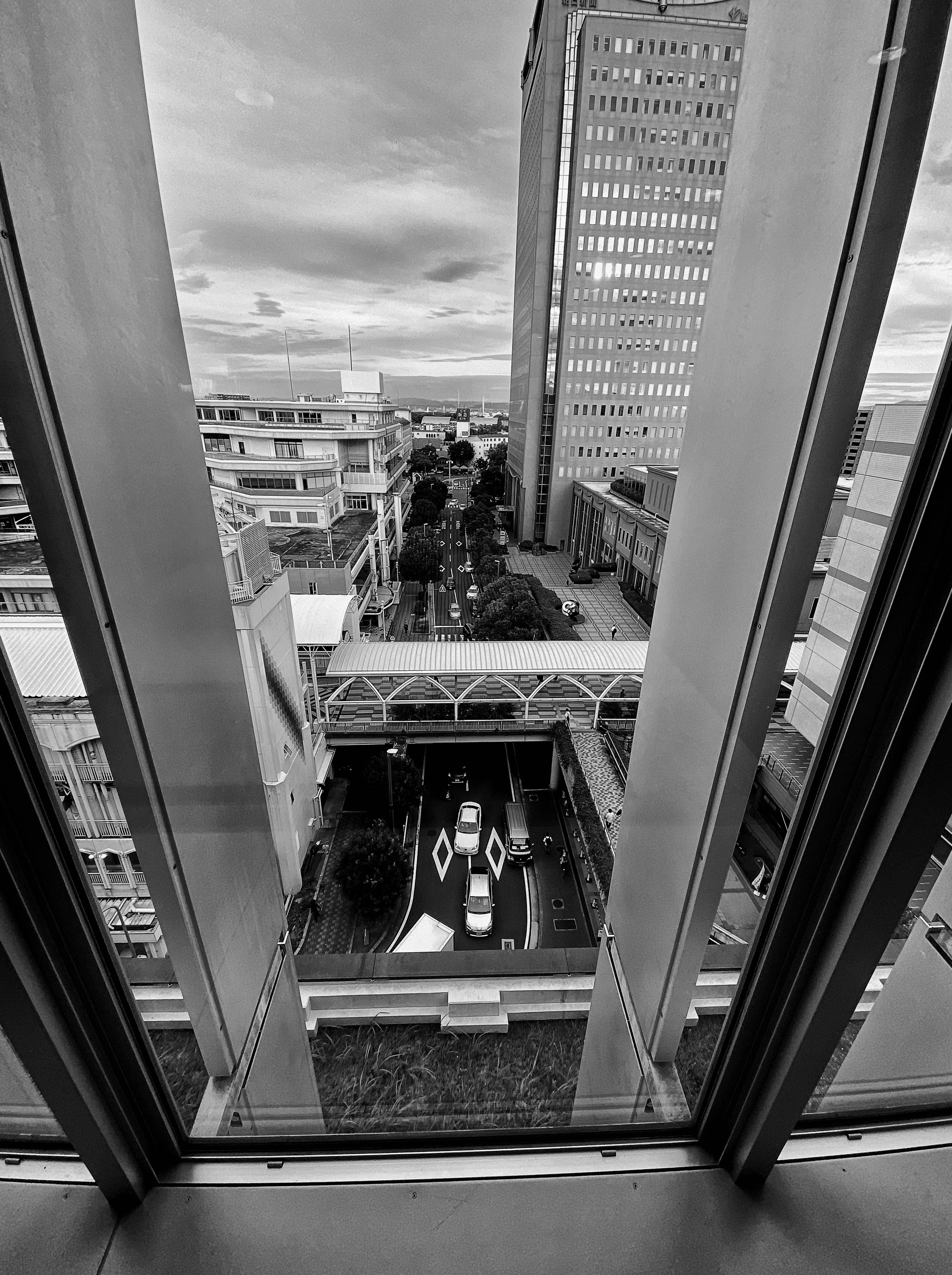 Black and white view from a high-rise building showcasing vehicles and an urban landscape