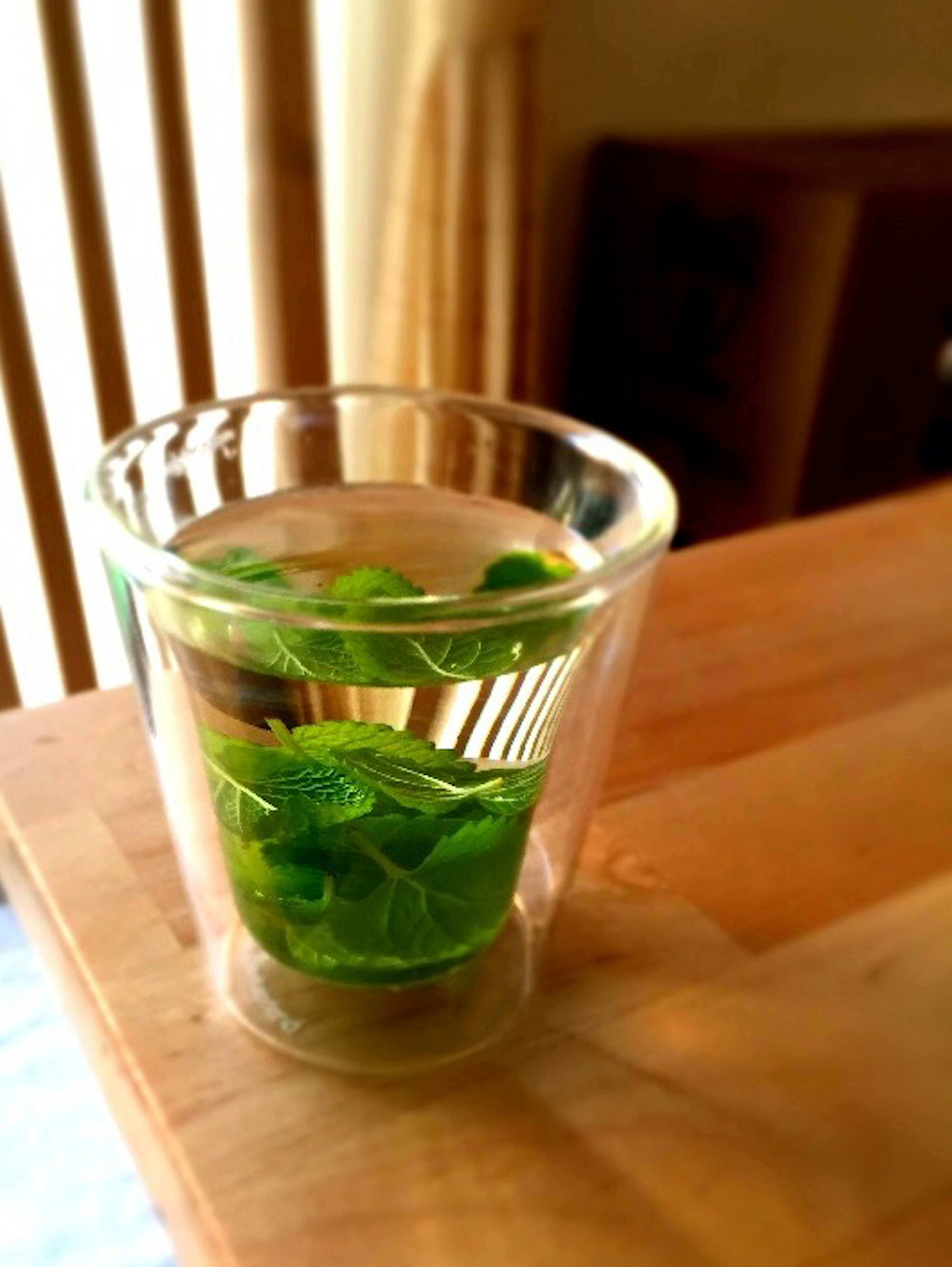 A transparent glass filled with water and fresh mint leaves