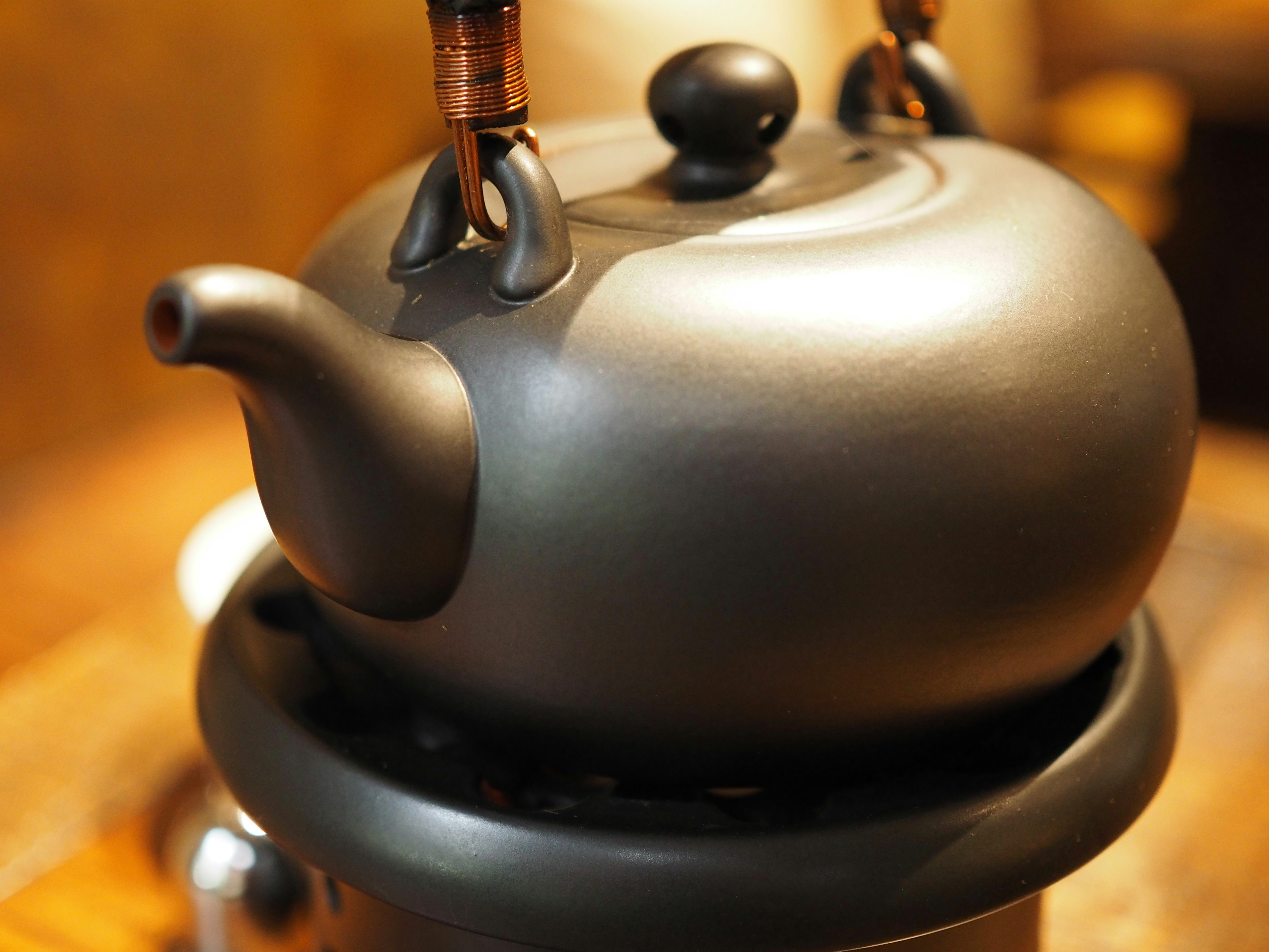 A close-up image of a black teapot on a wooden table