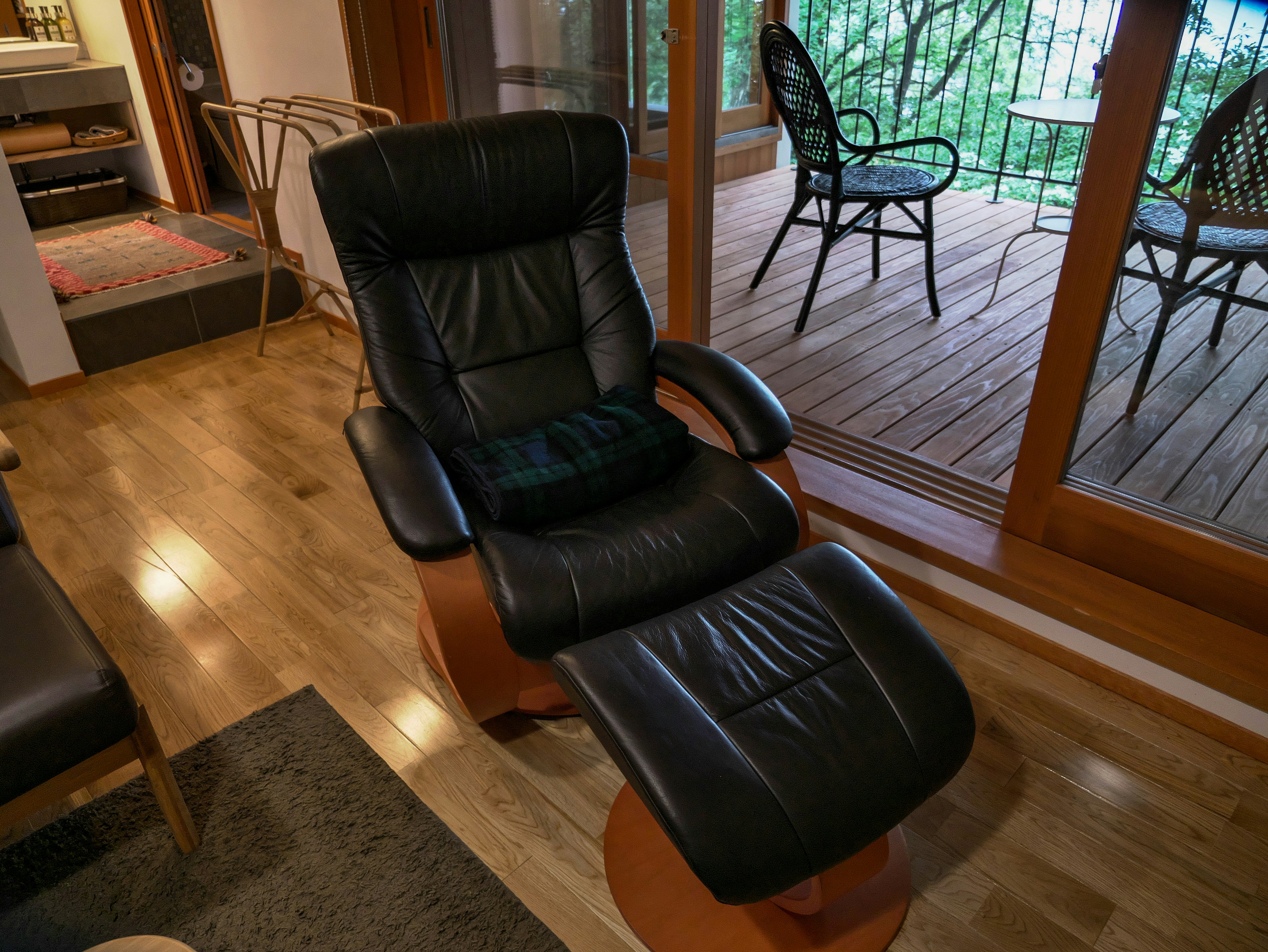 Sala de estar acogedora con un sillón reclinable de cuero negro y un ottomano