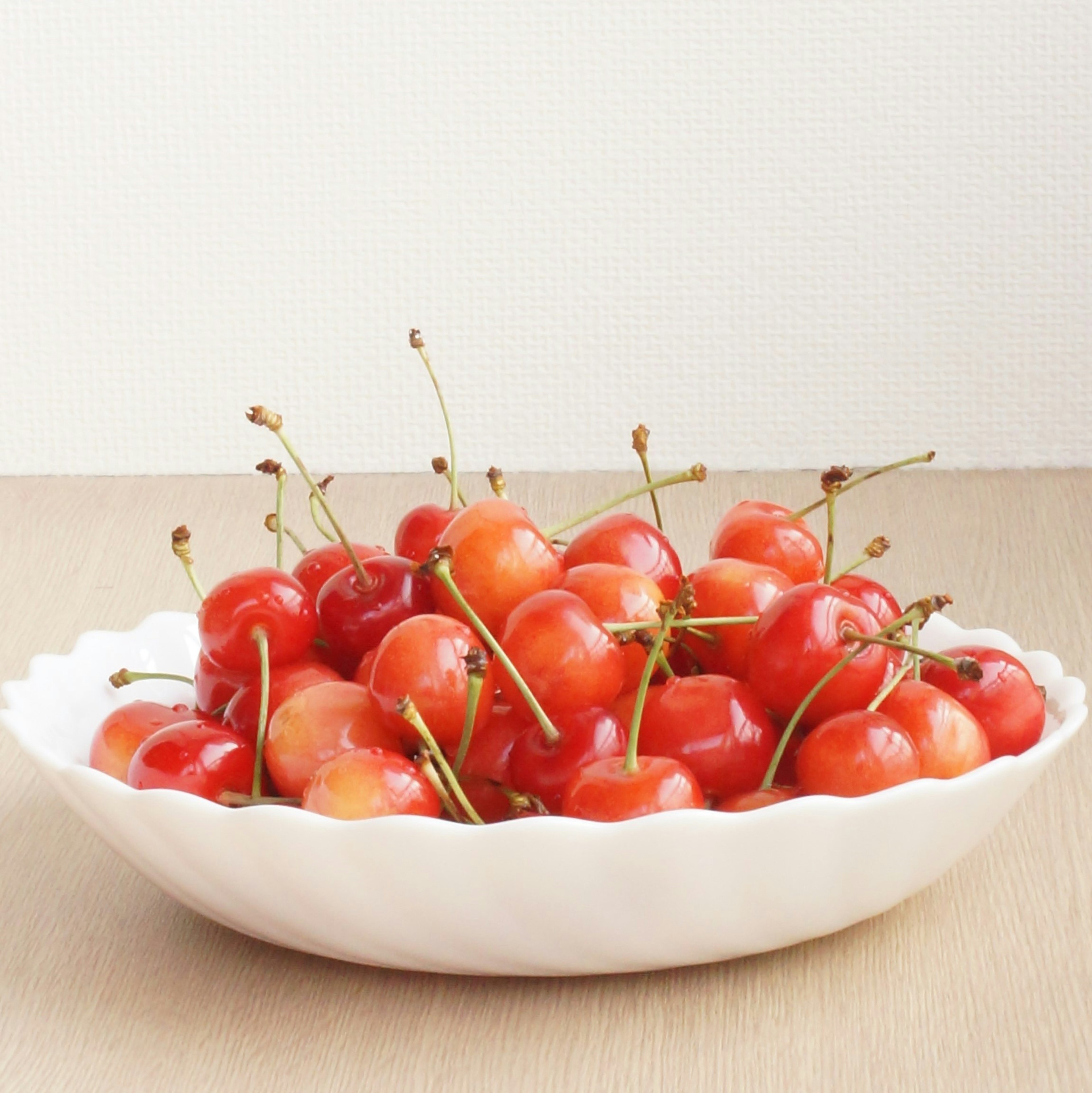 A mound of red cherries in a white scalloped bowl