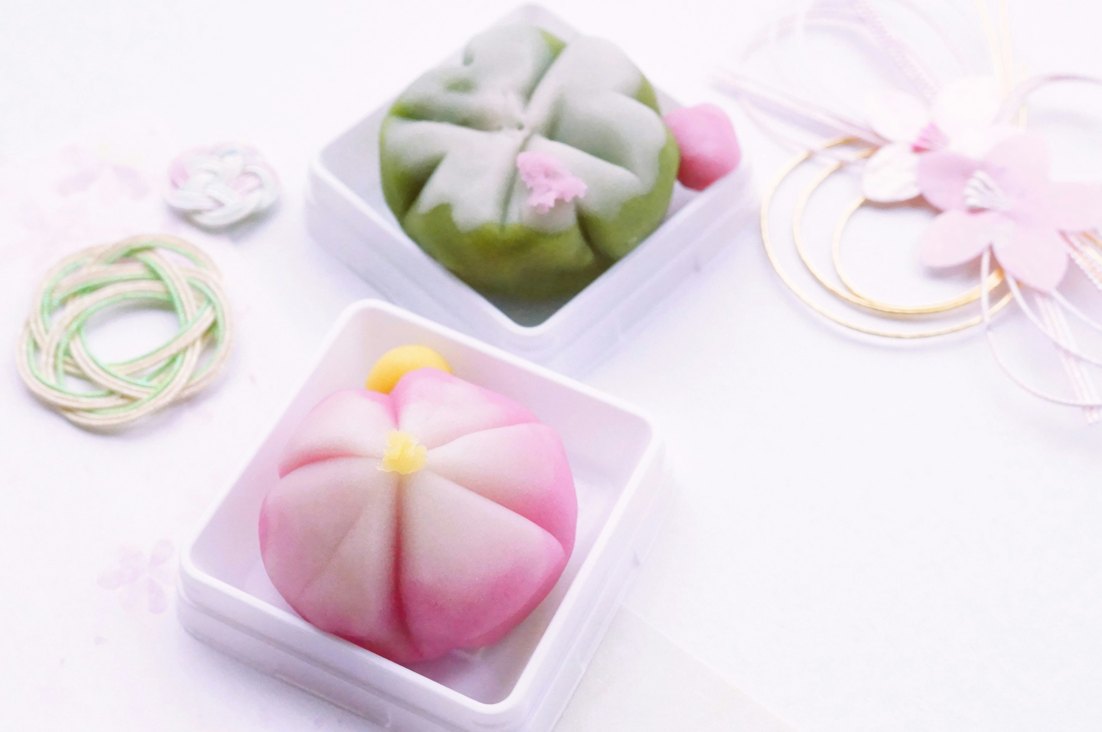 Beaux wagashi verts et roses disposés sur des assiettes blanches