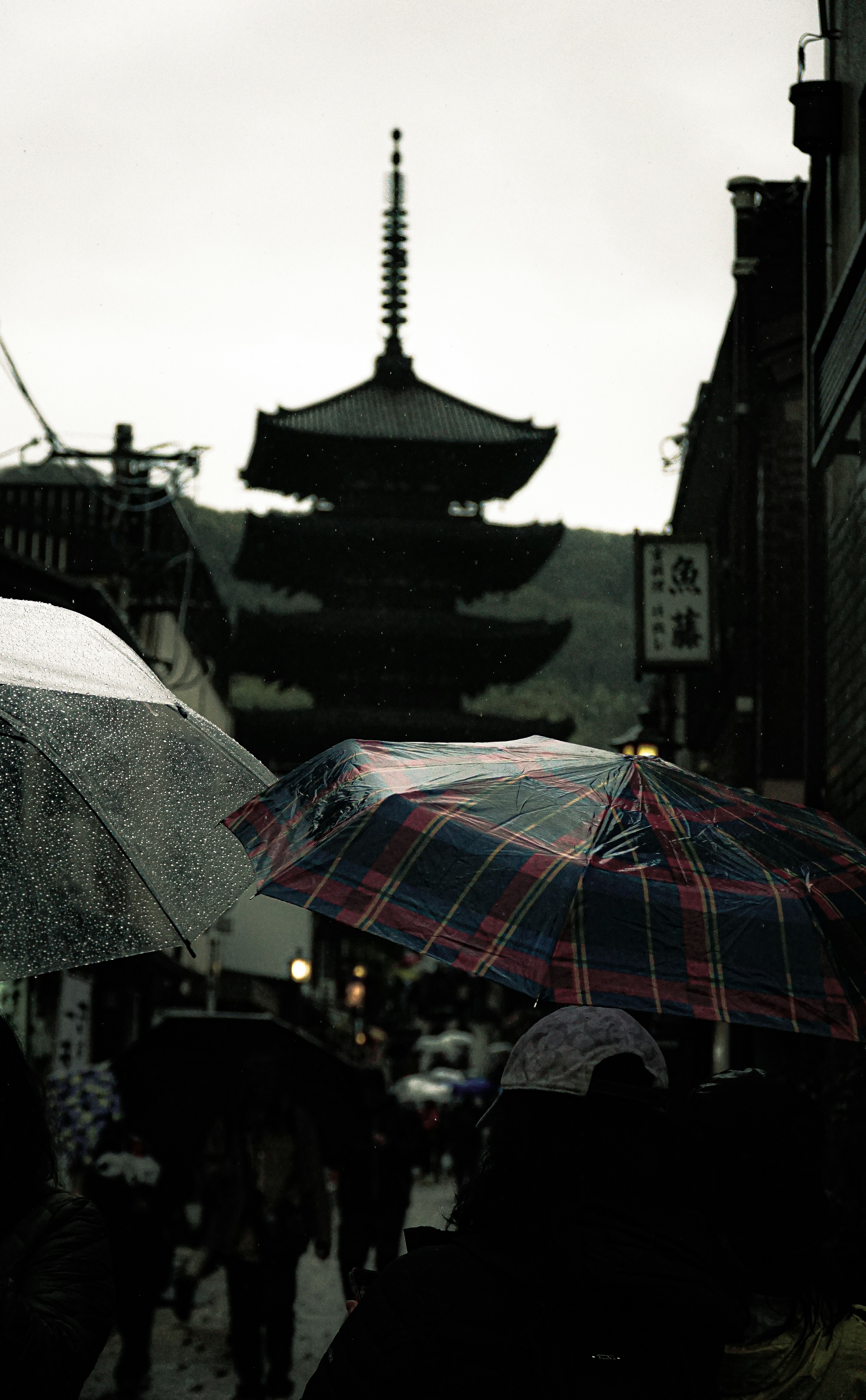 Personas con paraguas bajo la lluvia cerca de una pagoda