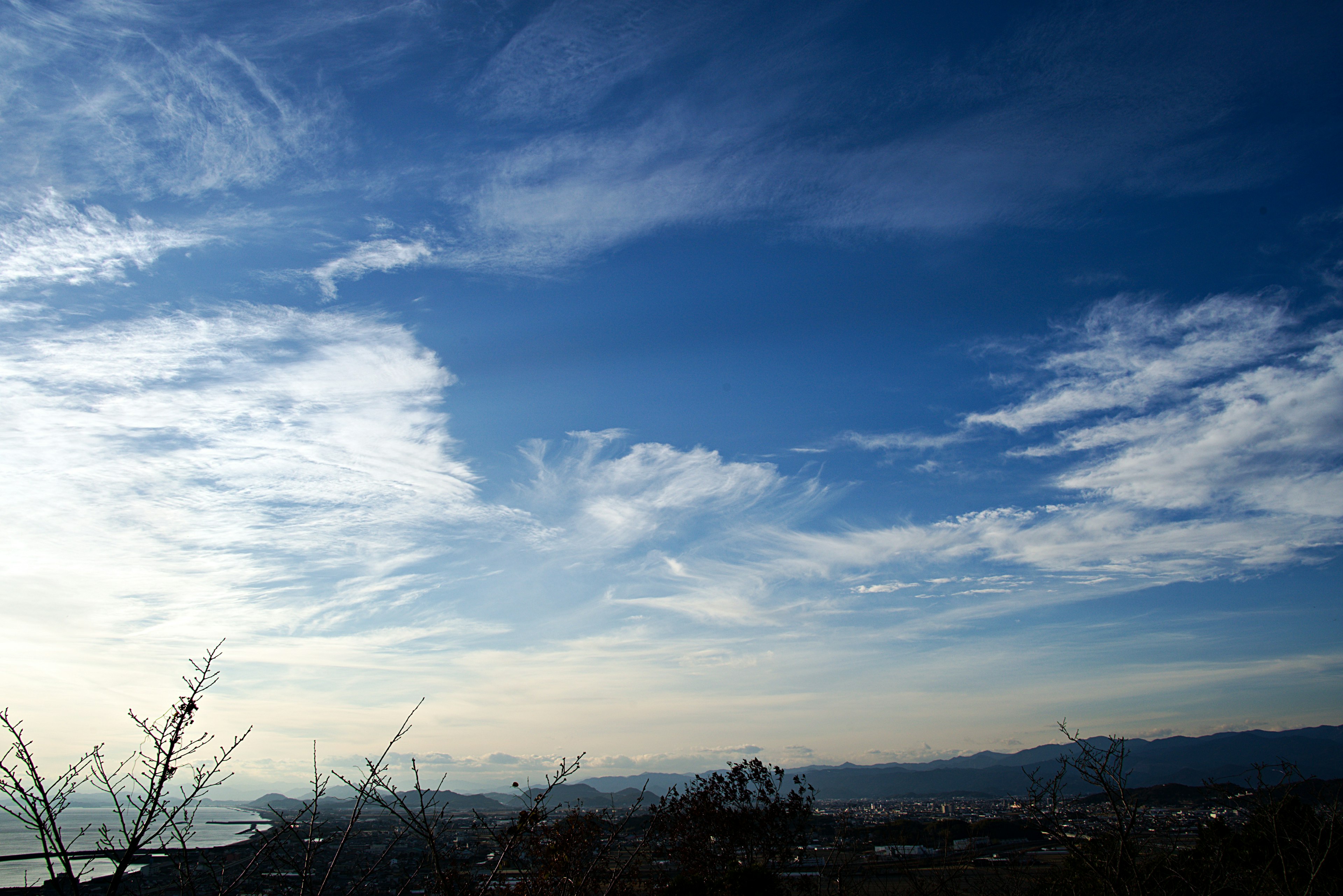 青空に白い雲が広がる風景と遠くの山々