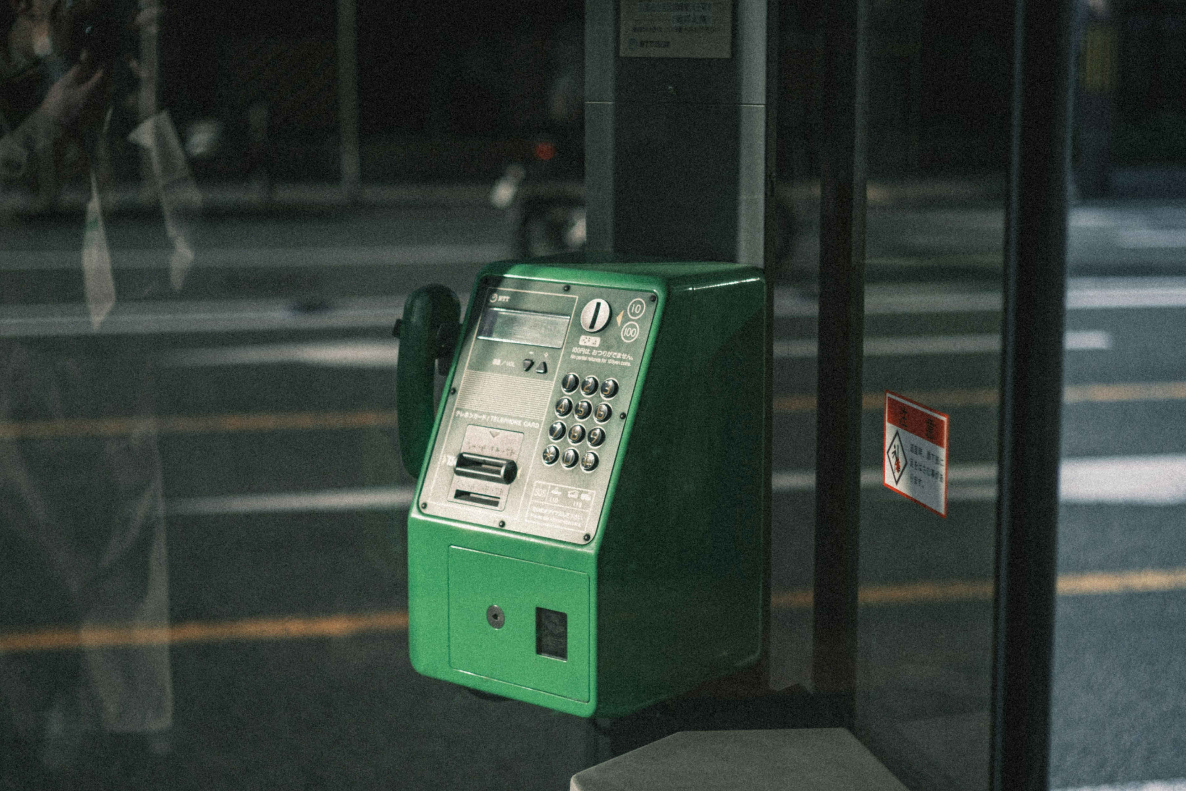 Una cabina telefónica pública verde ubicada en una esquina de la calle