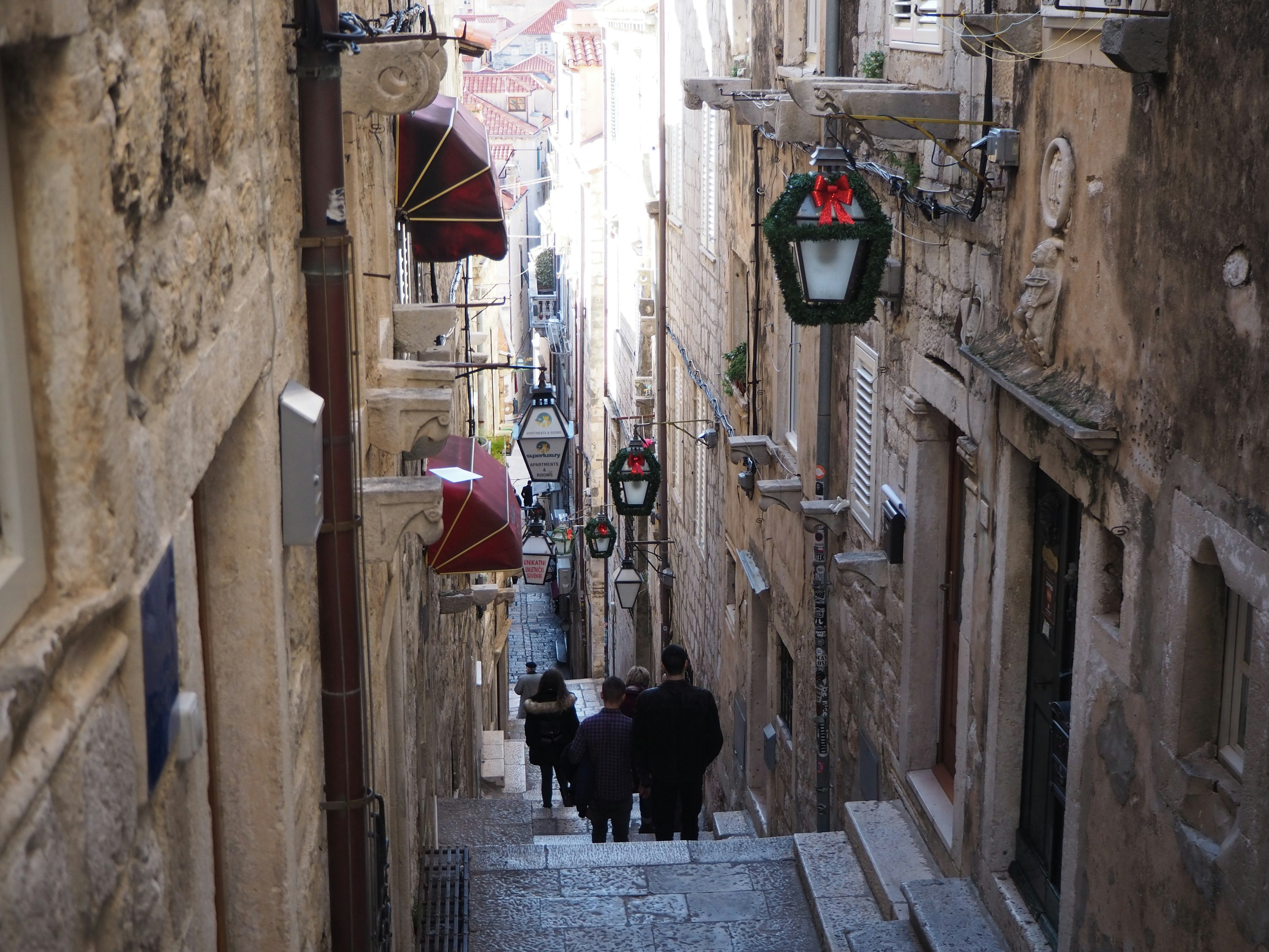 People walking down an old stone staircase with street lamps