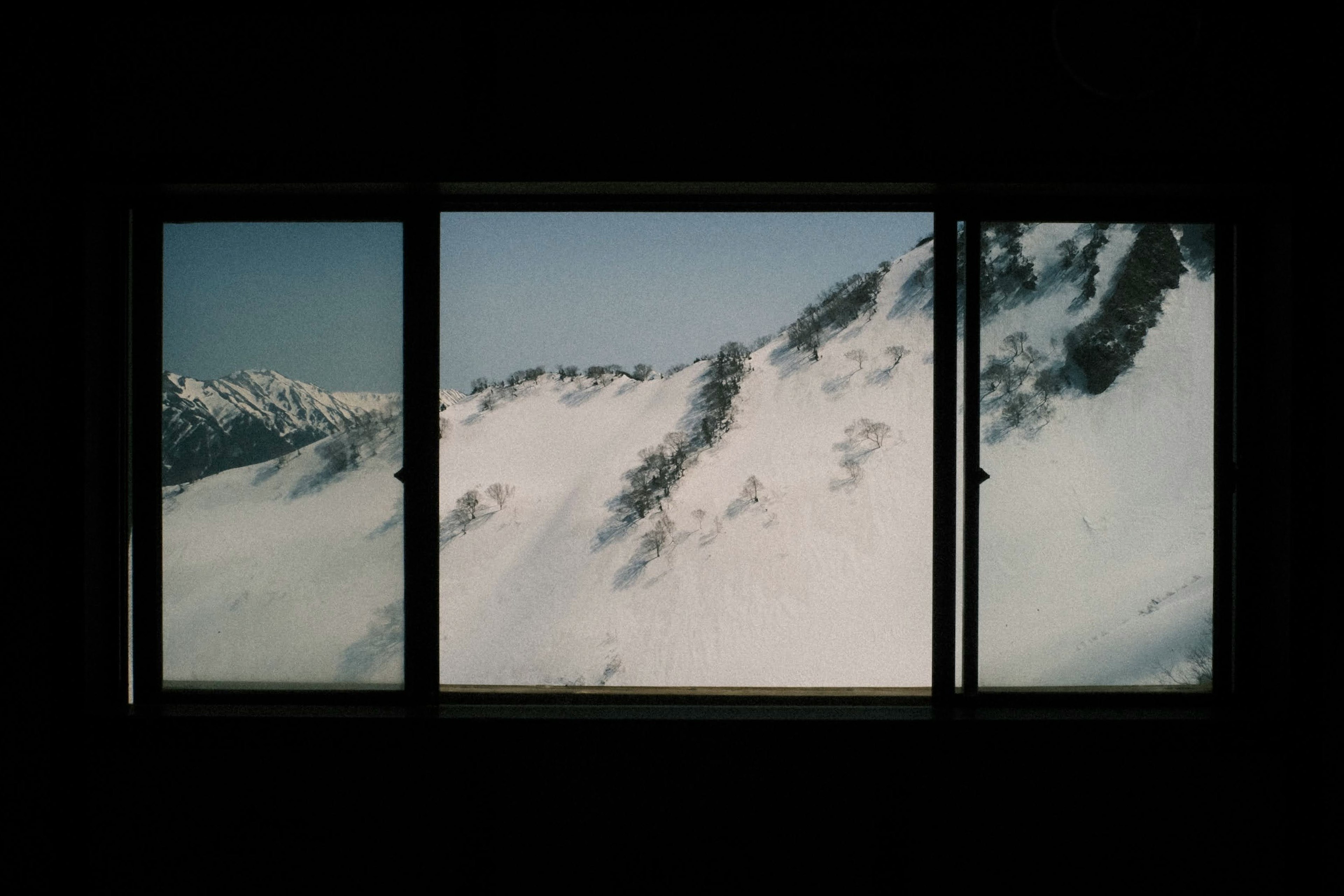 Tre finestre che incorniciano un paesaggio montano innevato