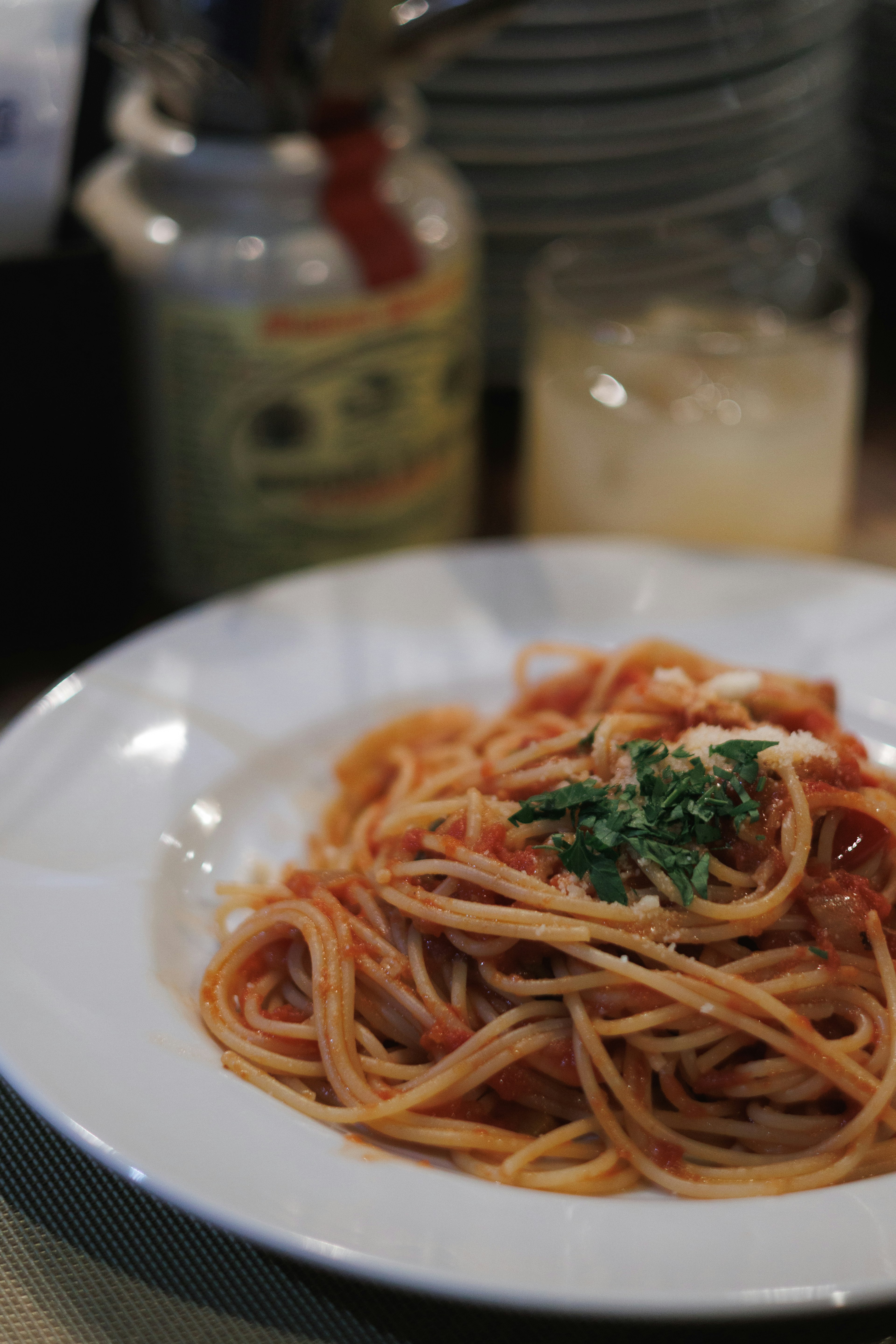 Spaghetti dengan saus tomat yang dihiasi peterseli di atas piring putih