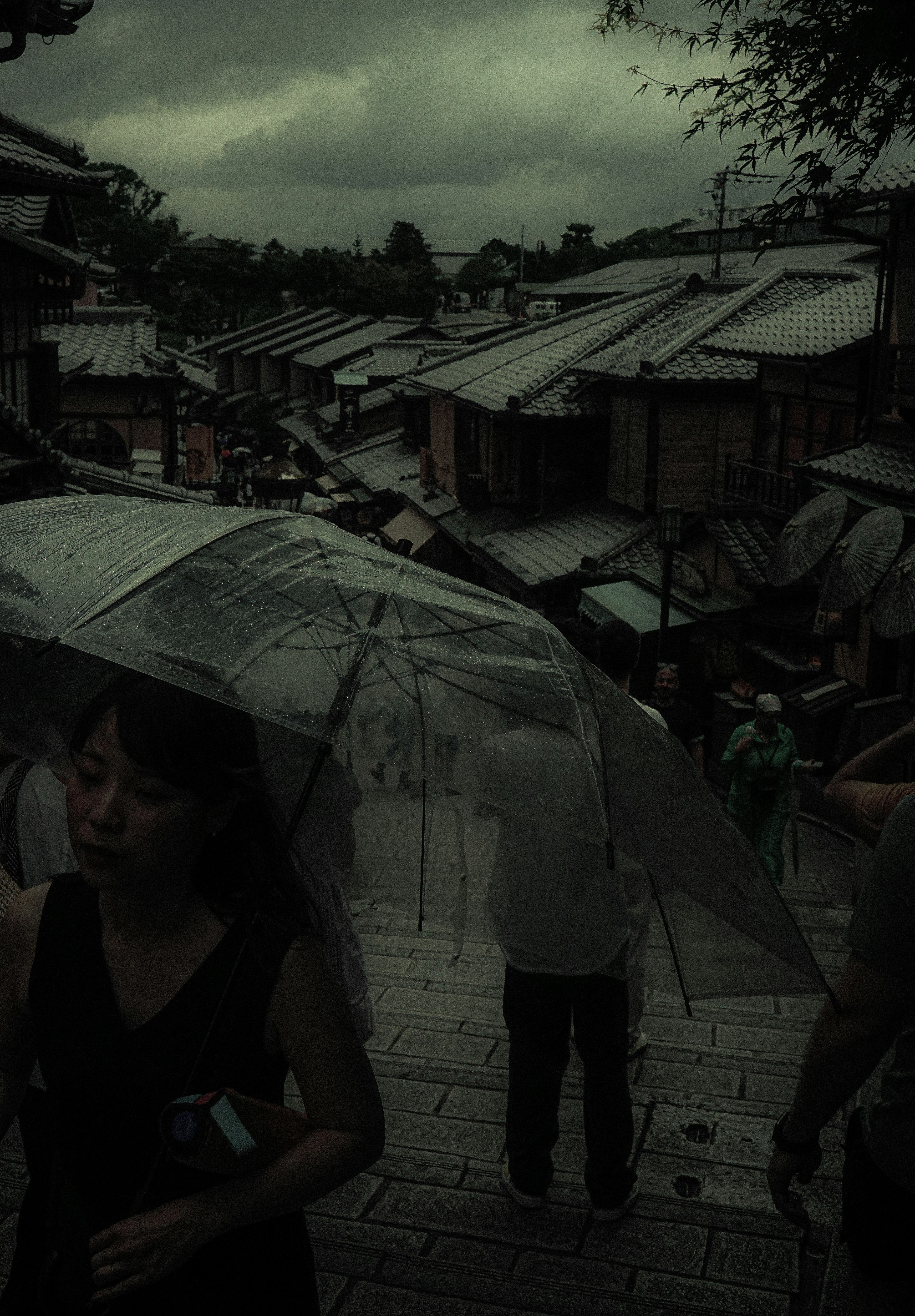 雨の中を歩く人々と曇り空の京都の風景