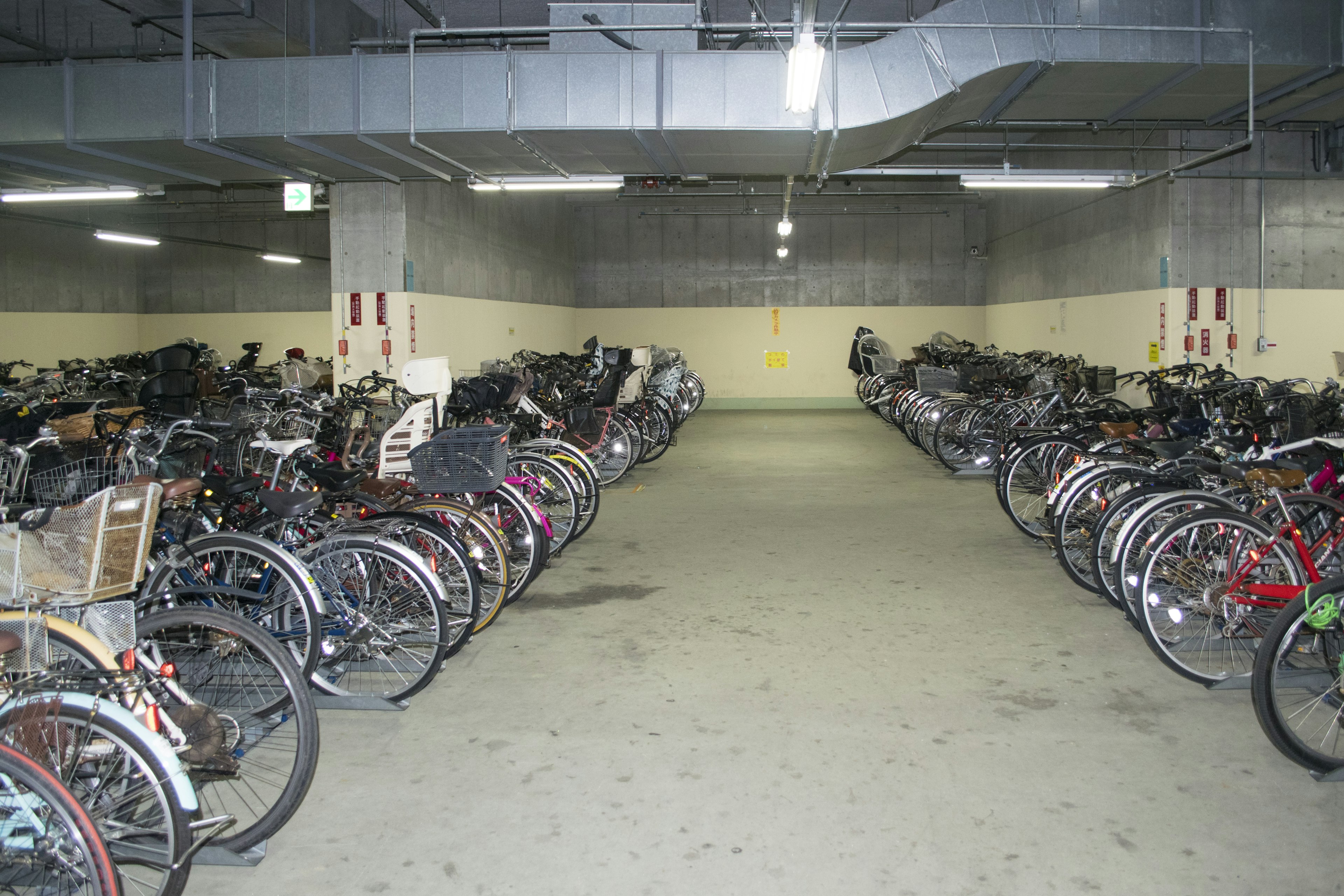 Bicycle parking area filled with numerous bicycles and bright lighting