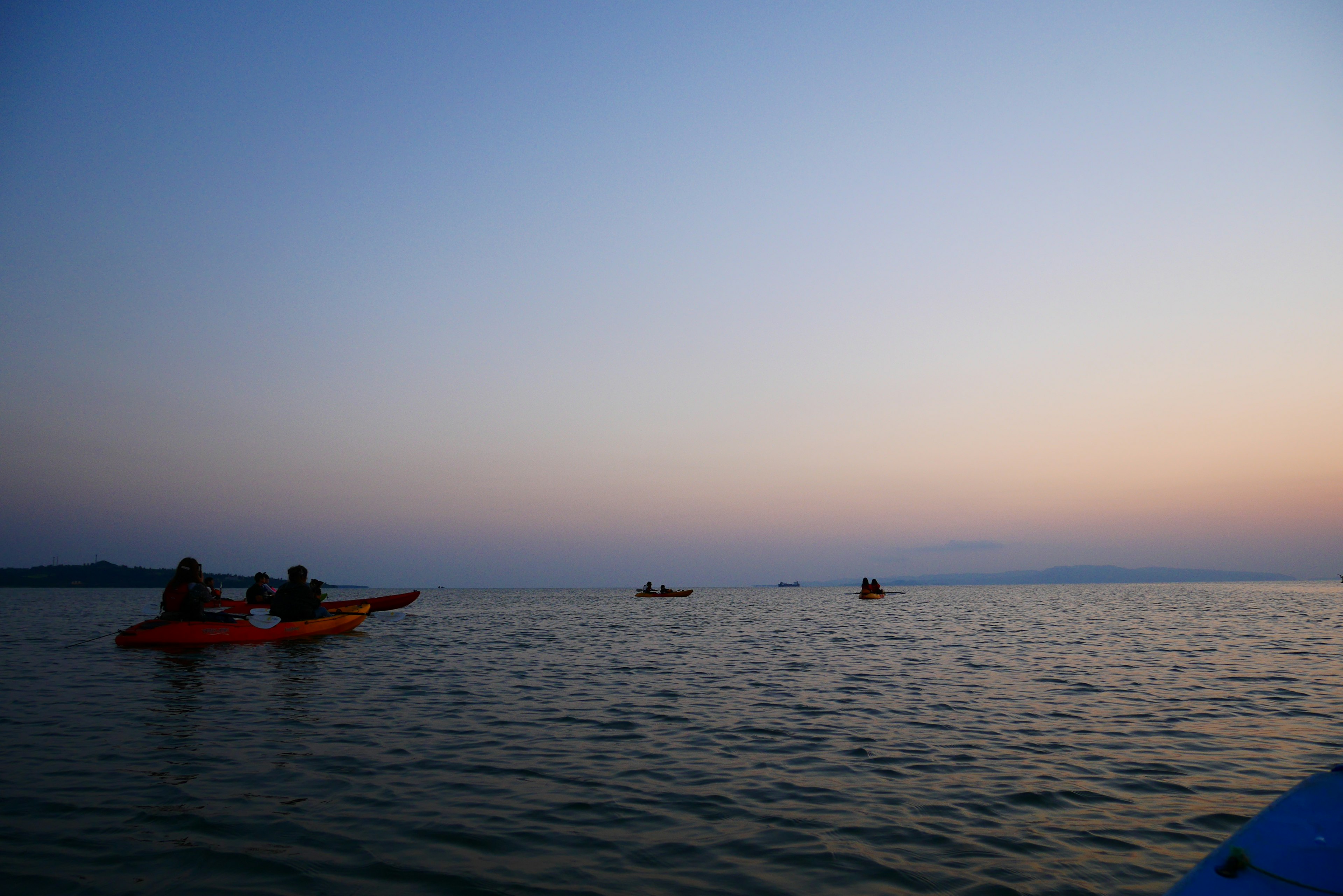 Siluetas de personas en kayak en un mar al atardecer