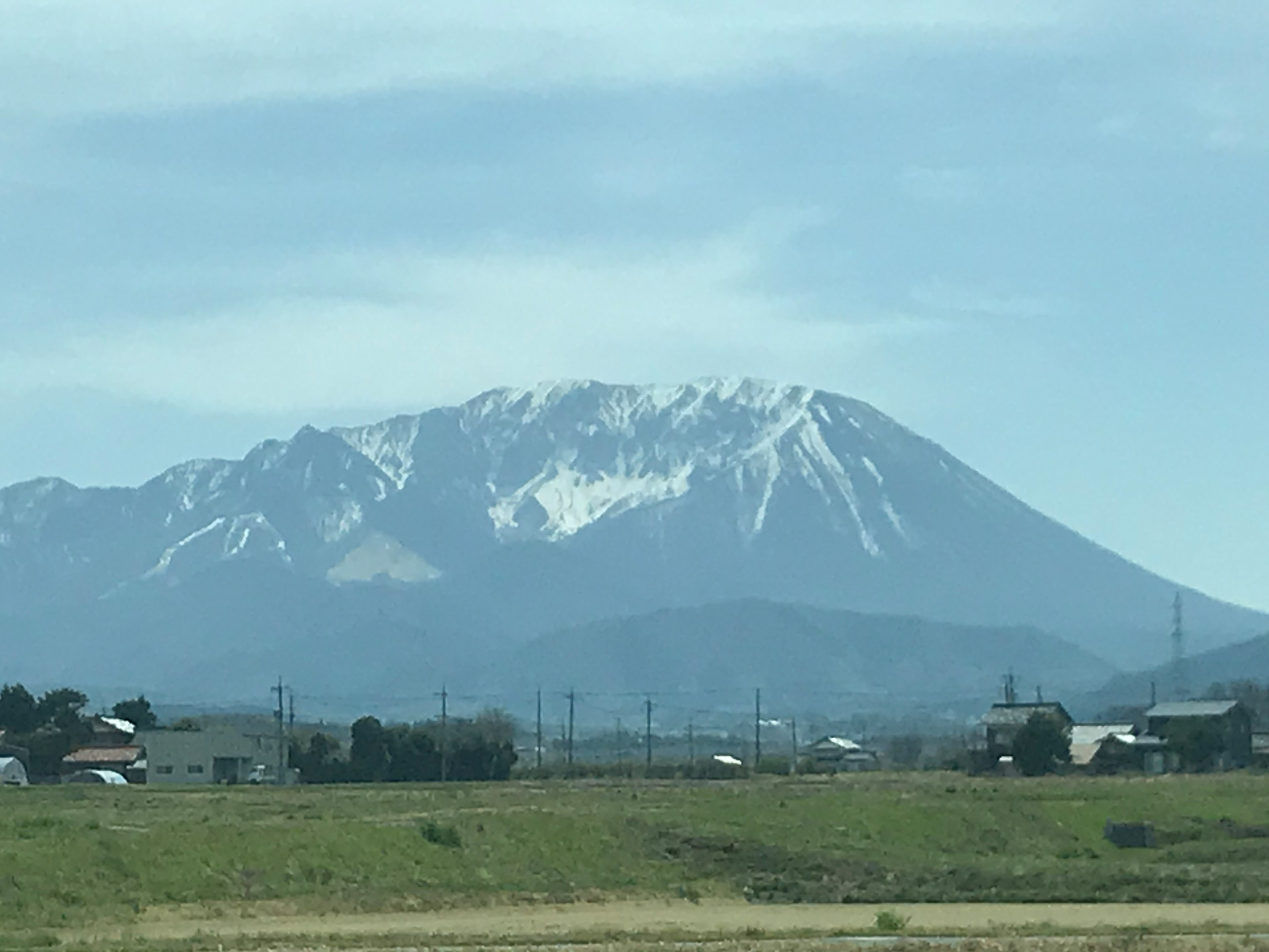 Snow-capped mountain with green fields in the foreground