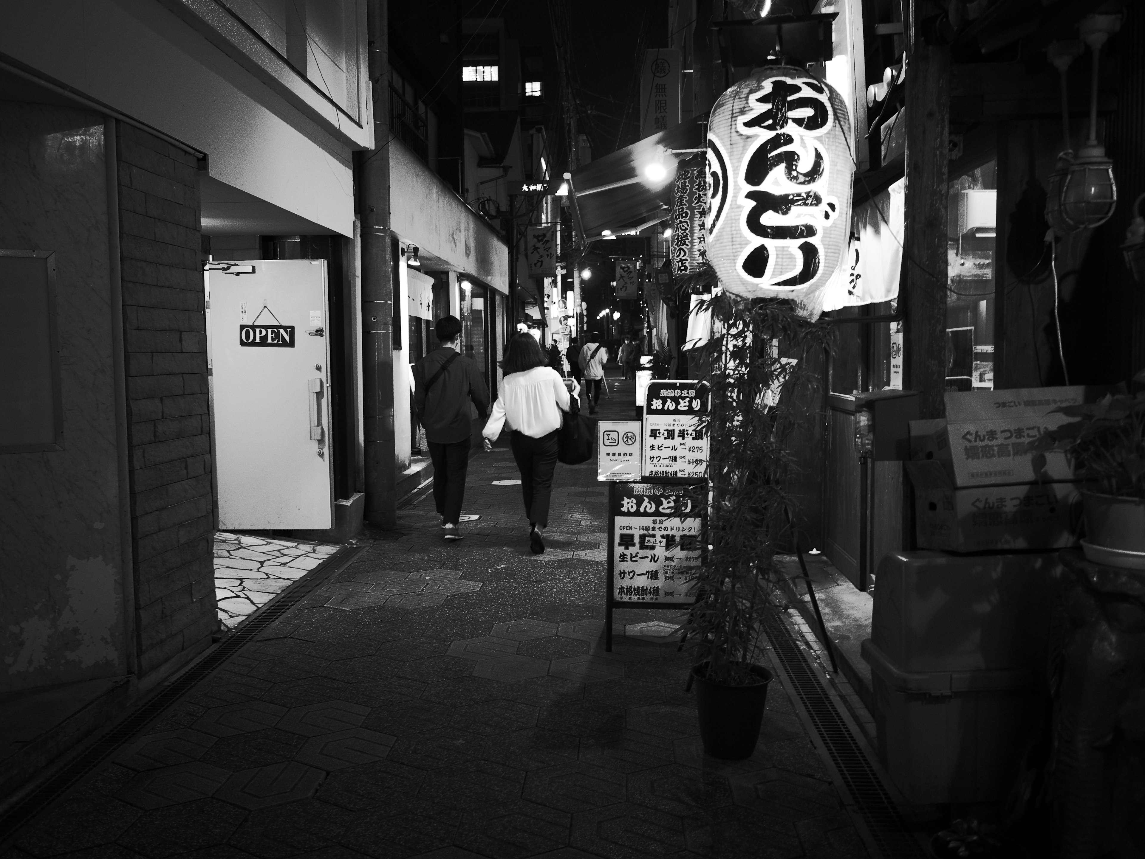 Personas caminando en una calle nocturna con señalización japonesa