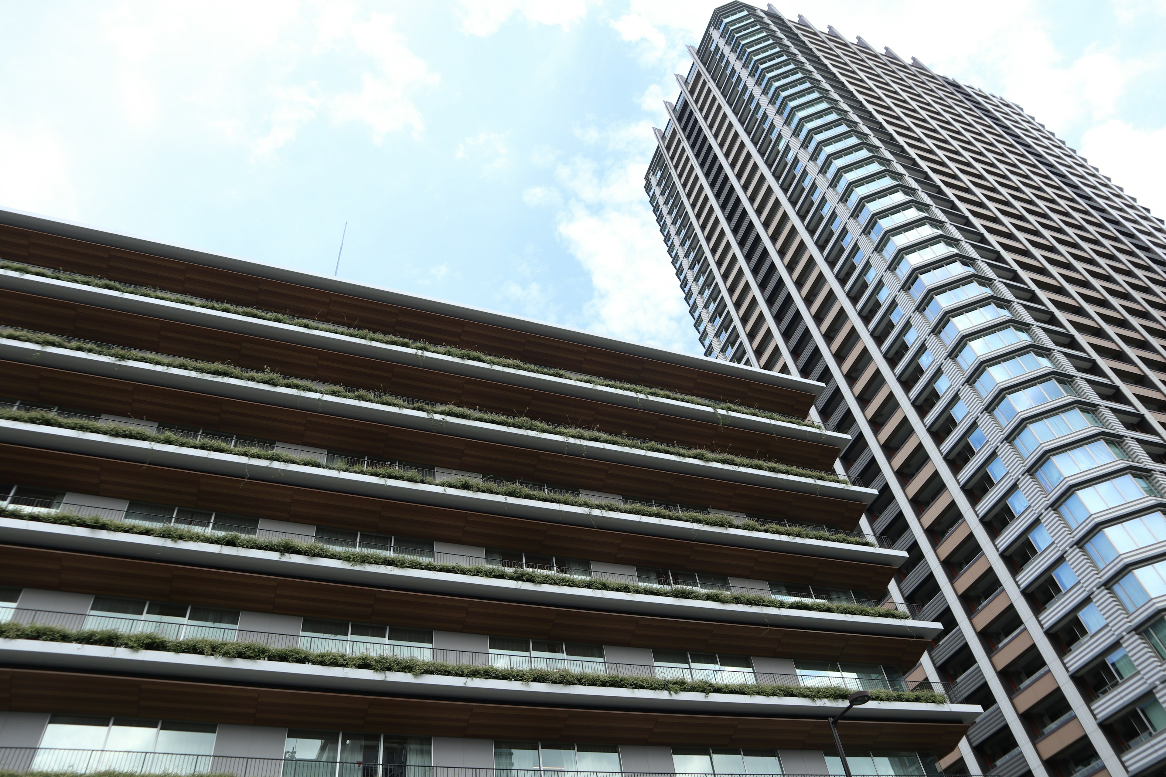 Photo showcasing a high-rise building next to a low-rise structure under a blue sky