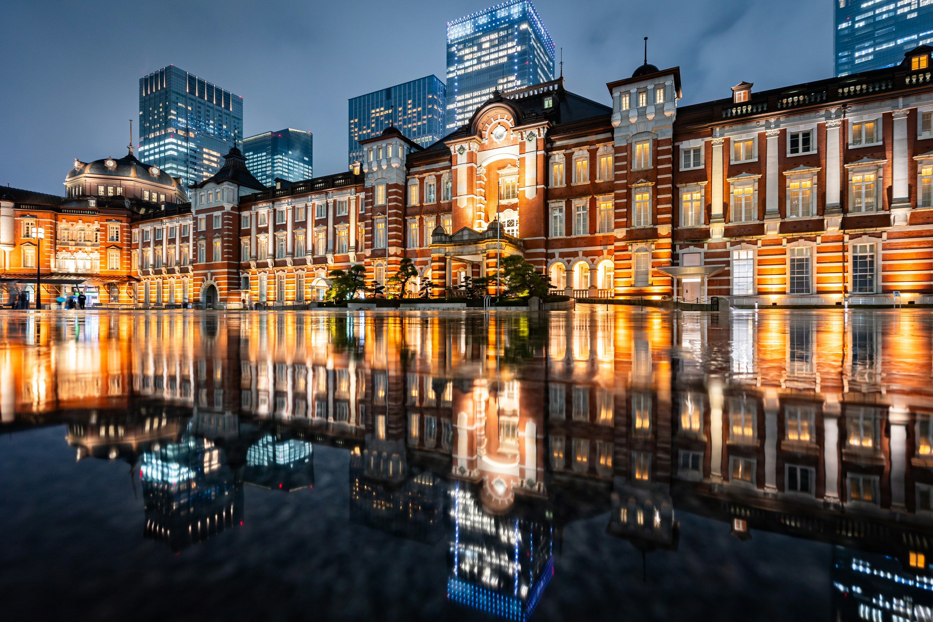 Hermosa vista nocturna de la estación de Tokio con reflejos en el agua