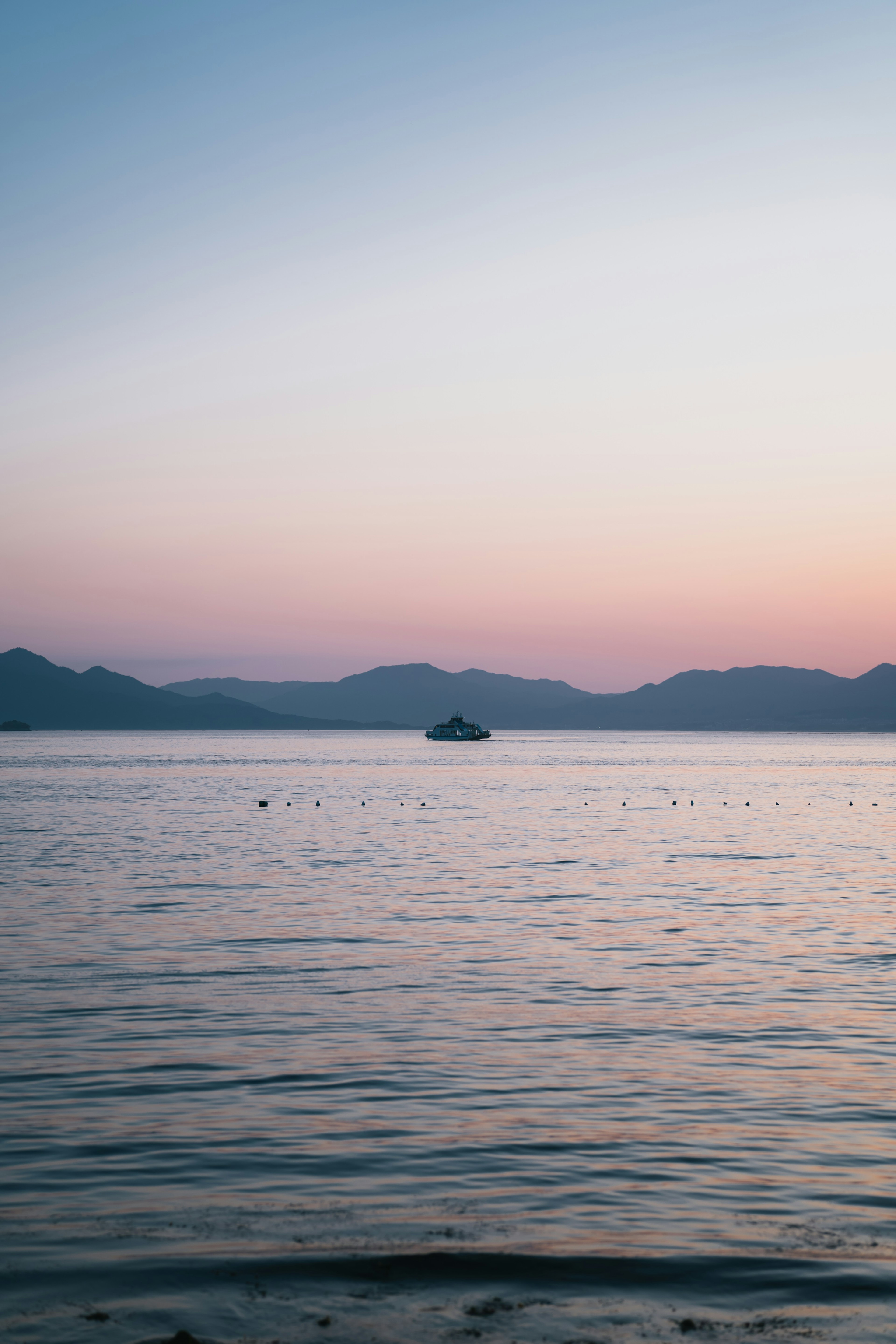 Tranquil lake at sunset with mountains and boat in the distance