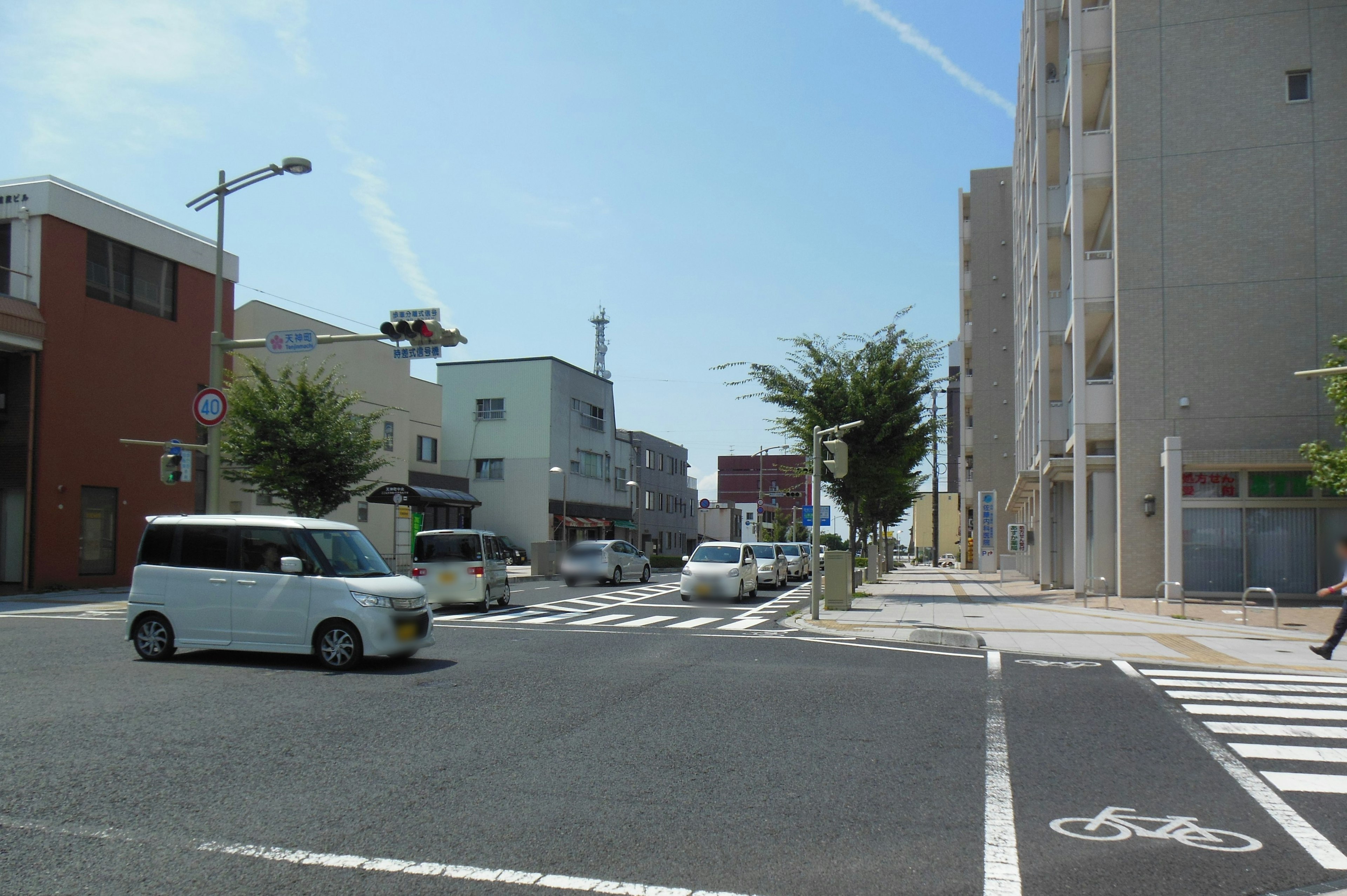 Intersection in a quiet neighborhood under a blue sky featuring white cars and buildings