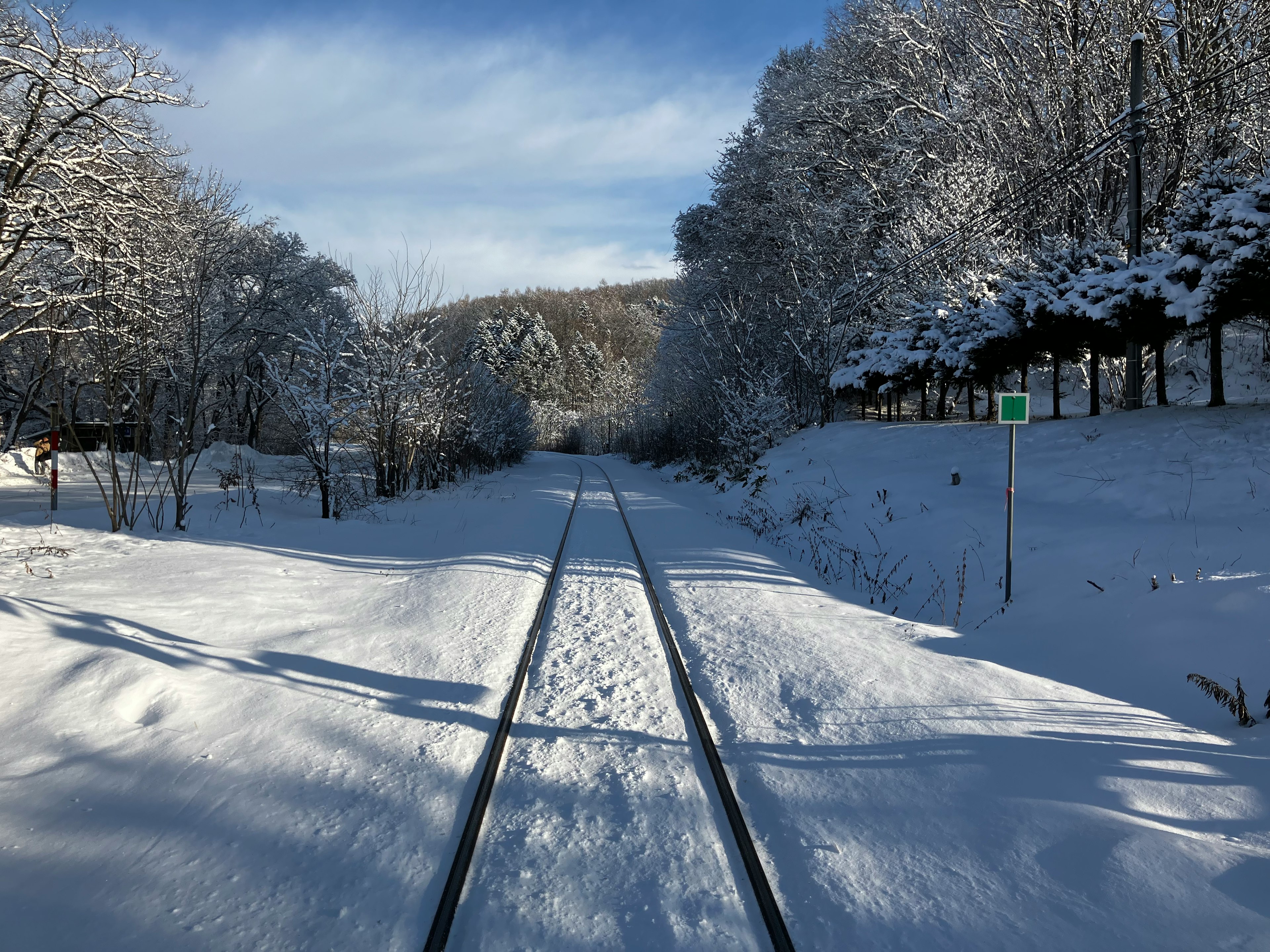 Paysage ferroviaire recouvert de neige Rails menant à travers une profonde neige Arbres bordant le chemin sous un ciel bleu