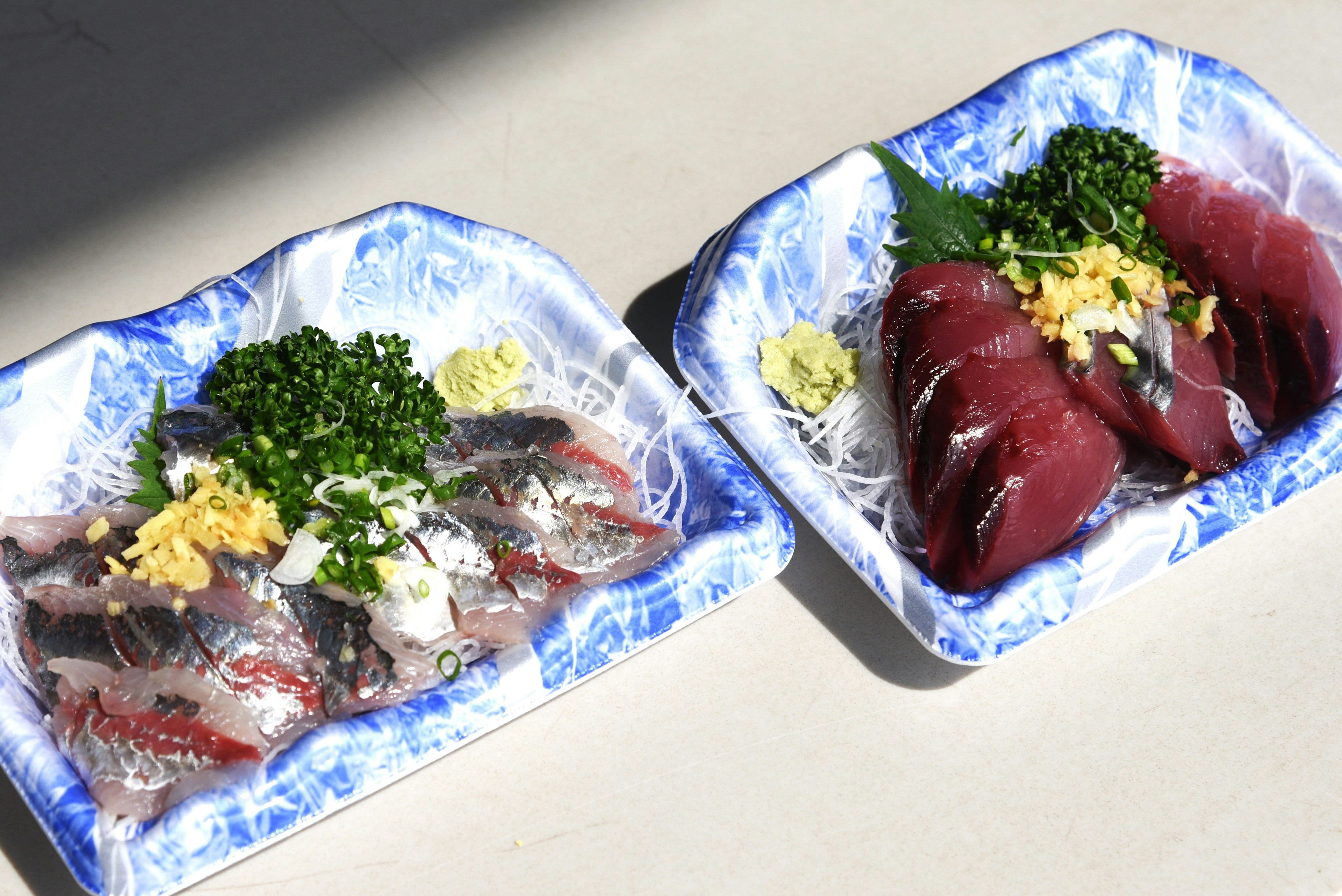 Frischer Sashimi- und Sushi-Teller auf blauen Tellern mit Ingwer und Wasabi