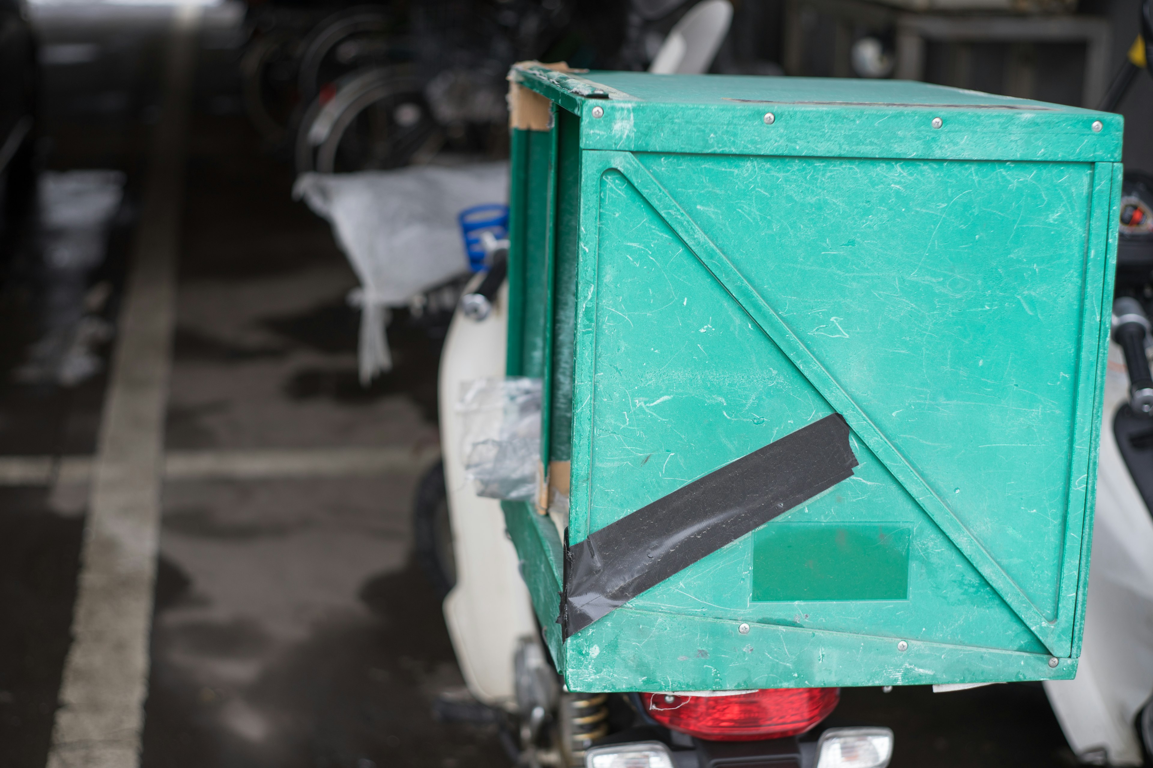 Una caja de entrega verde adjunta a la parte trasera de una motocicleta