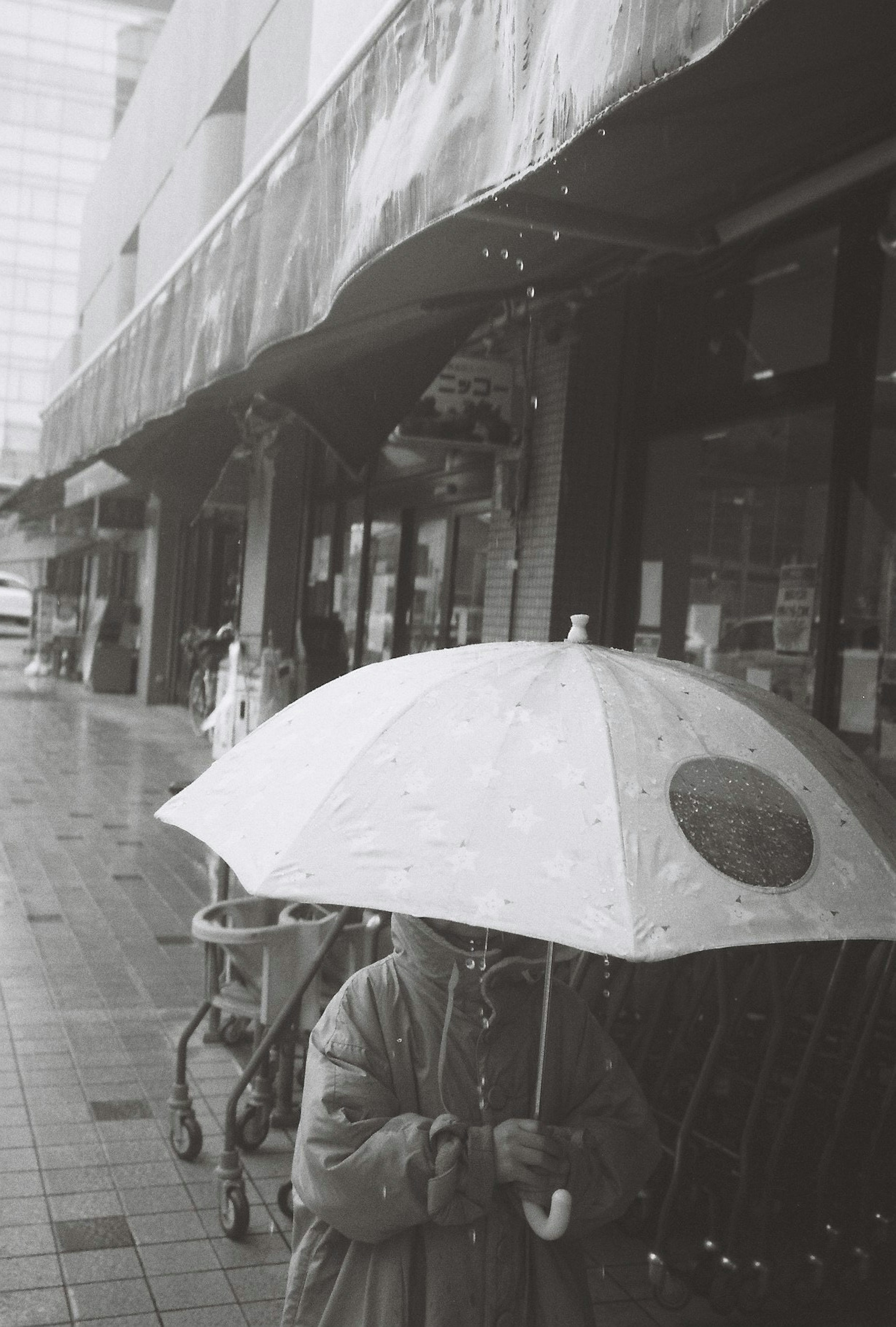 Enfant tenant un parapluie blanc marchant dans la rue en noir et blanc