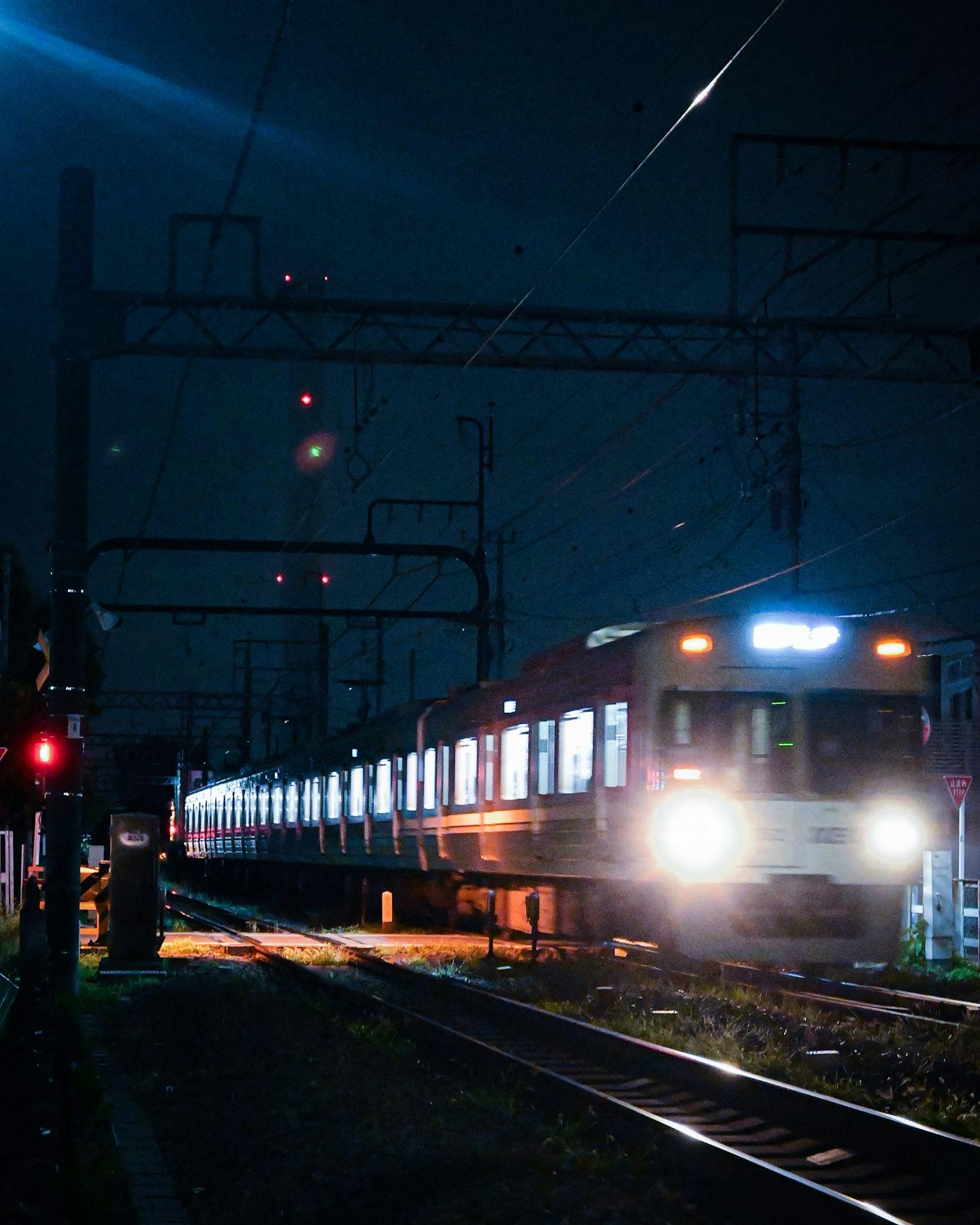 Treno in movimento in una stazione ferroviaria notturna con segnali luminosi