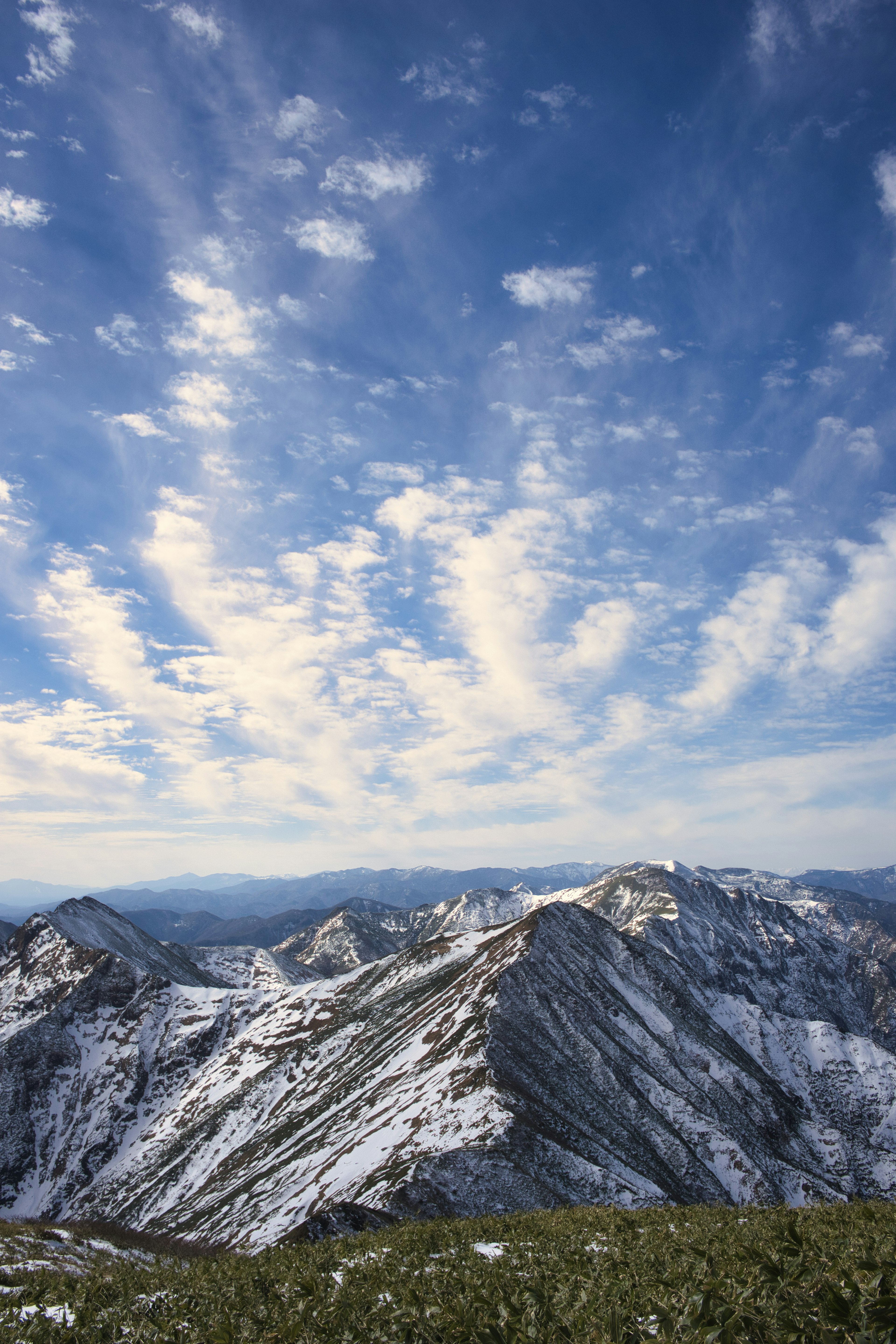 Snow-covered mountains under a blue sky with scattered clouds