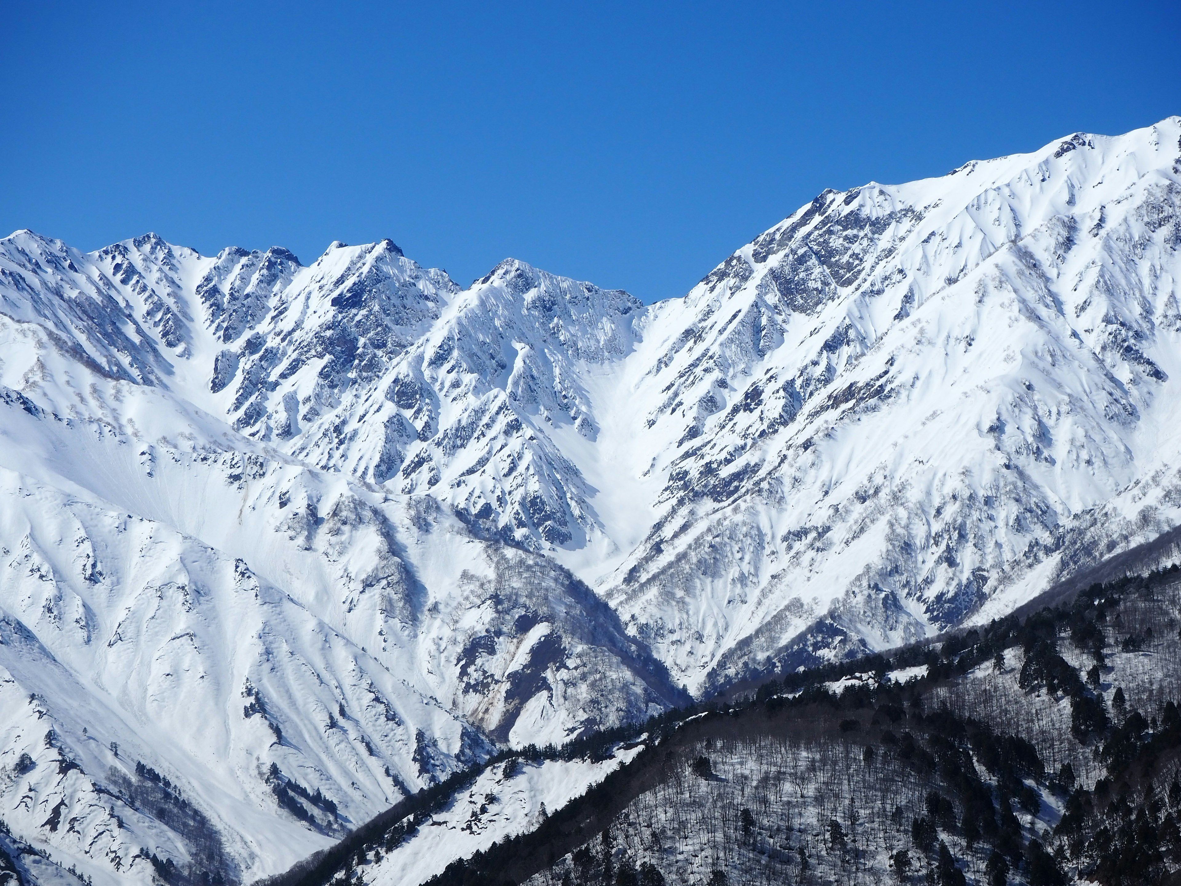 Snow-covered mountain peaks against a clear blue sky