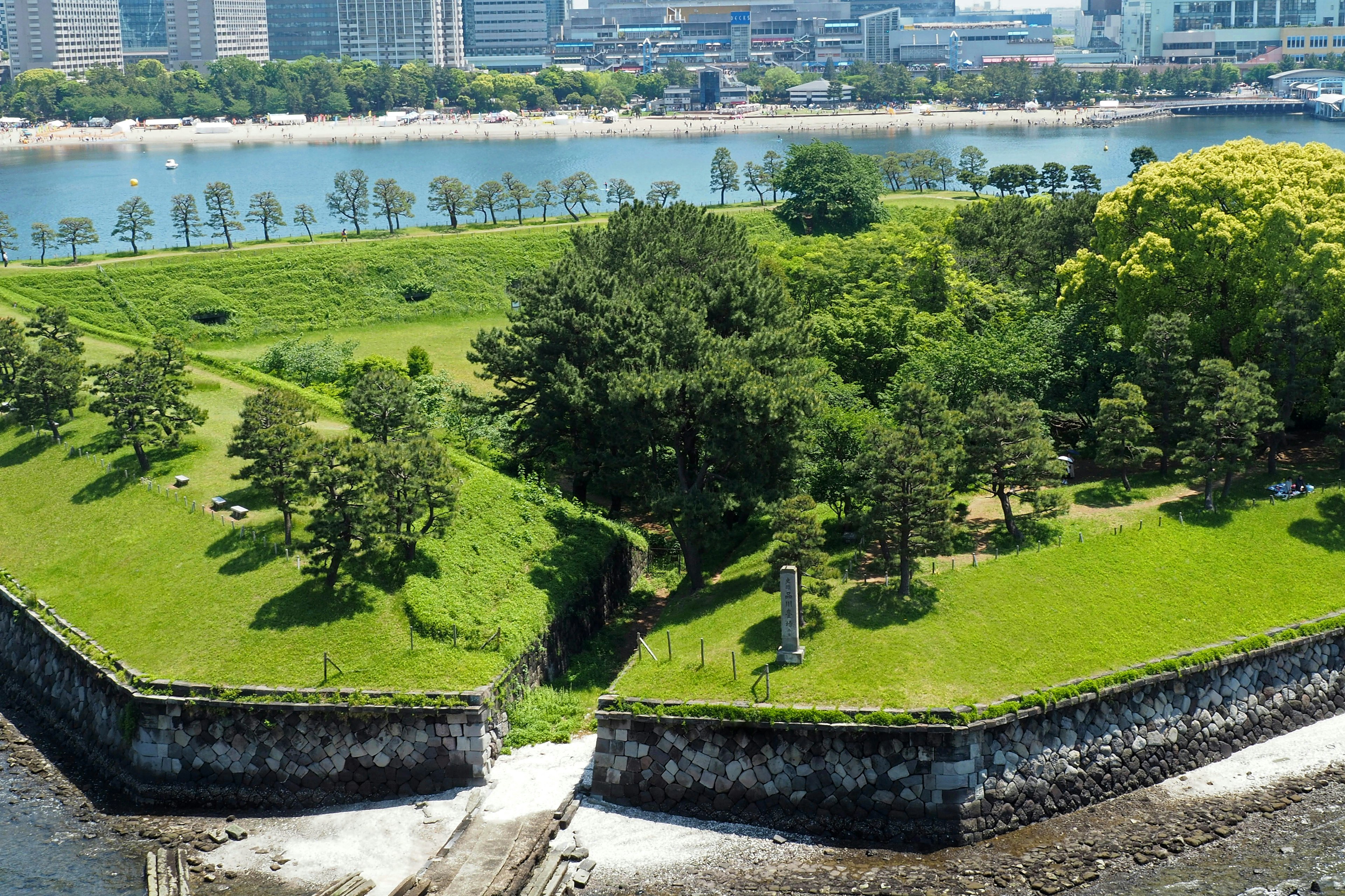 Lush green park with waterfront view and historic stone walls