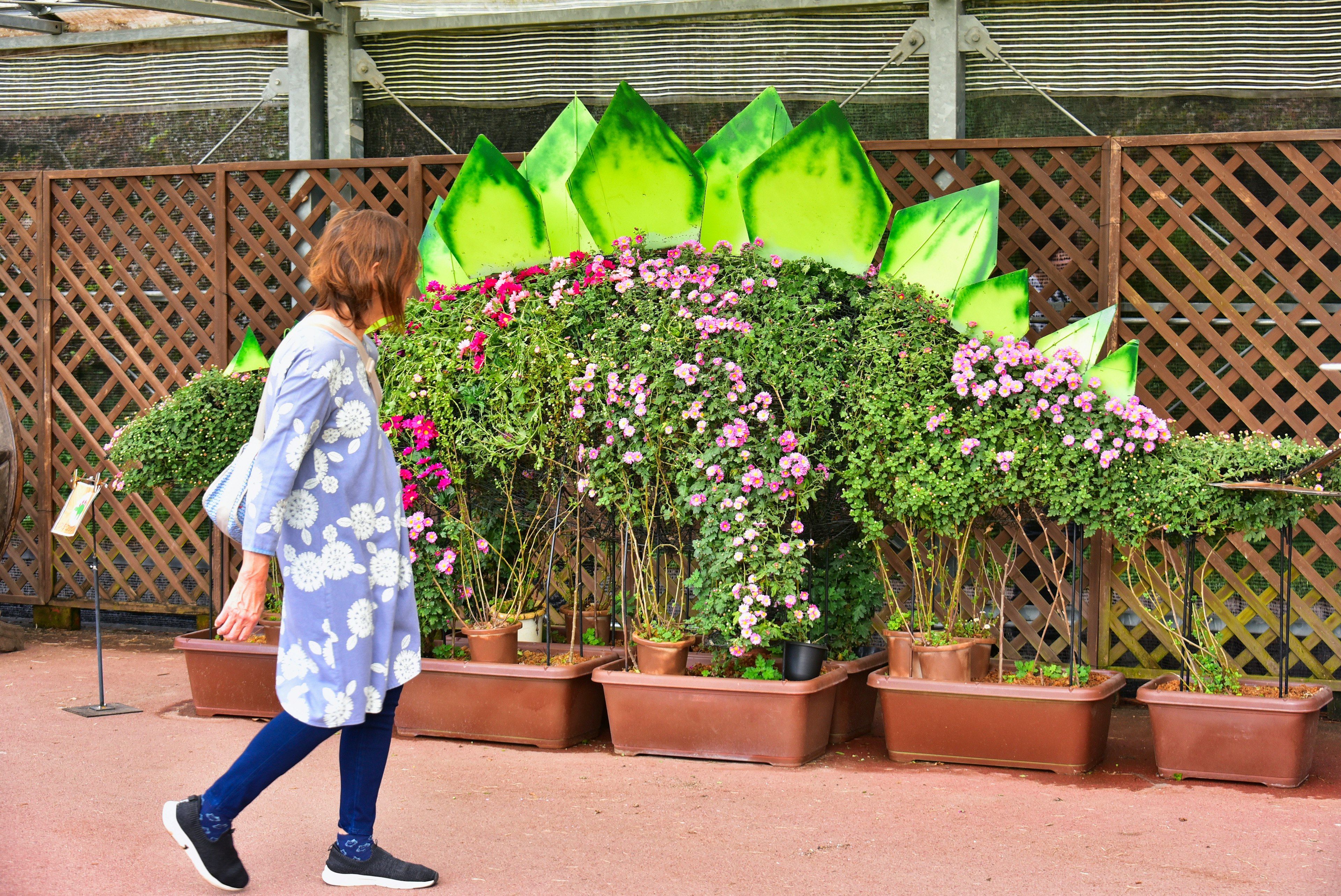 Eine Frau, die an einer dekorativen grünen Pflanzenausstellung mit Blumen vorbeigeht