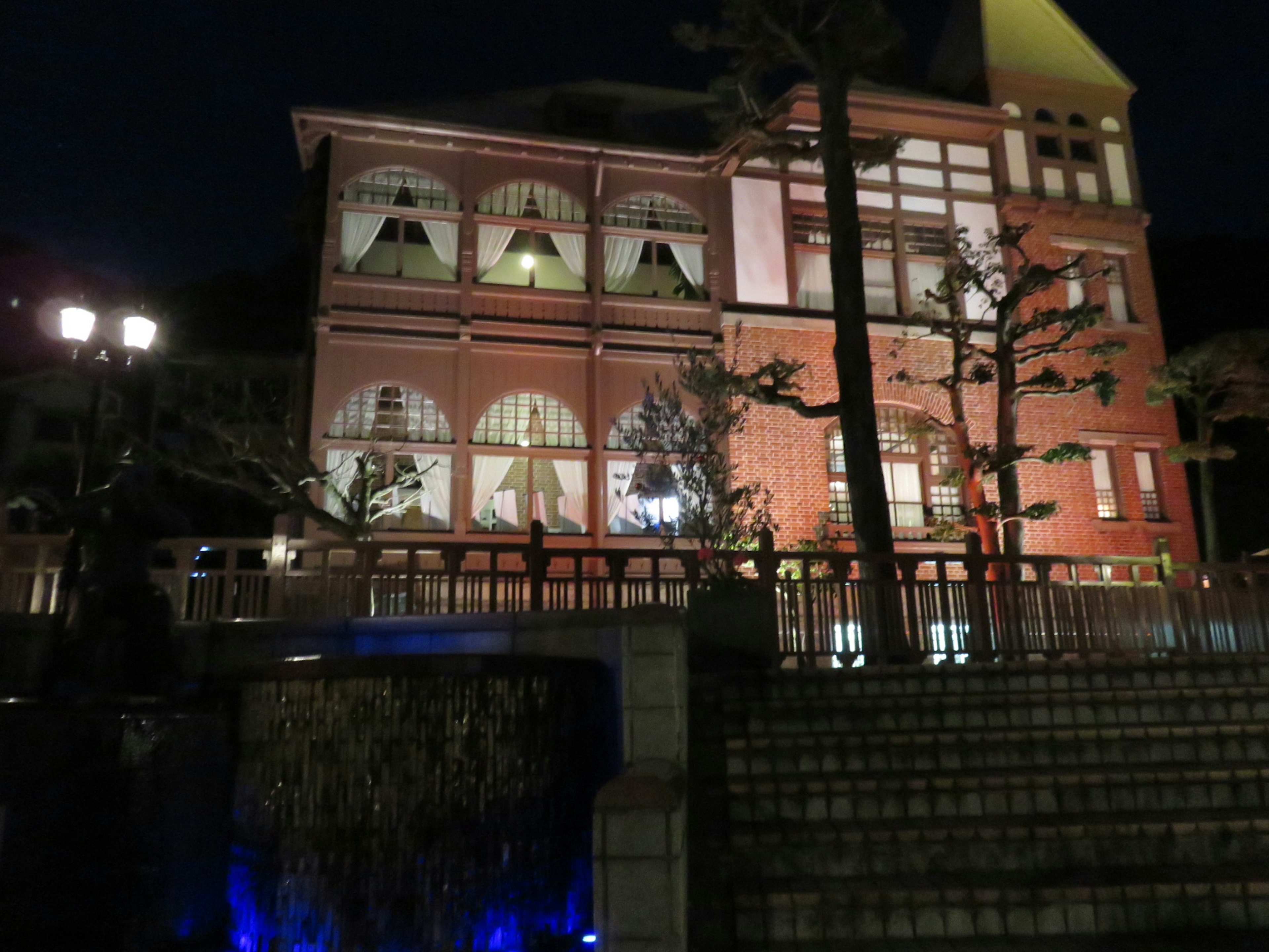 Red brick building illuminated at night with surrounding trees