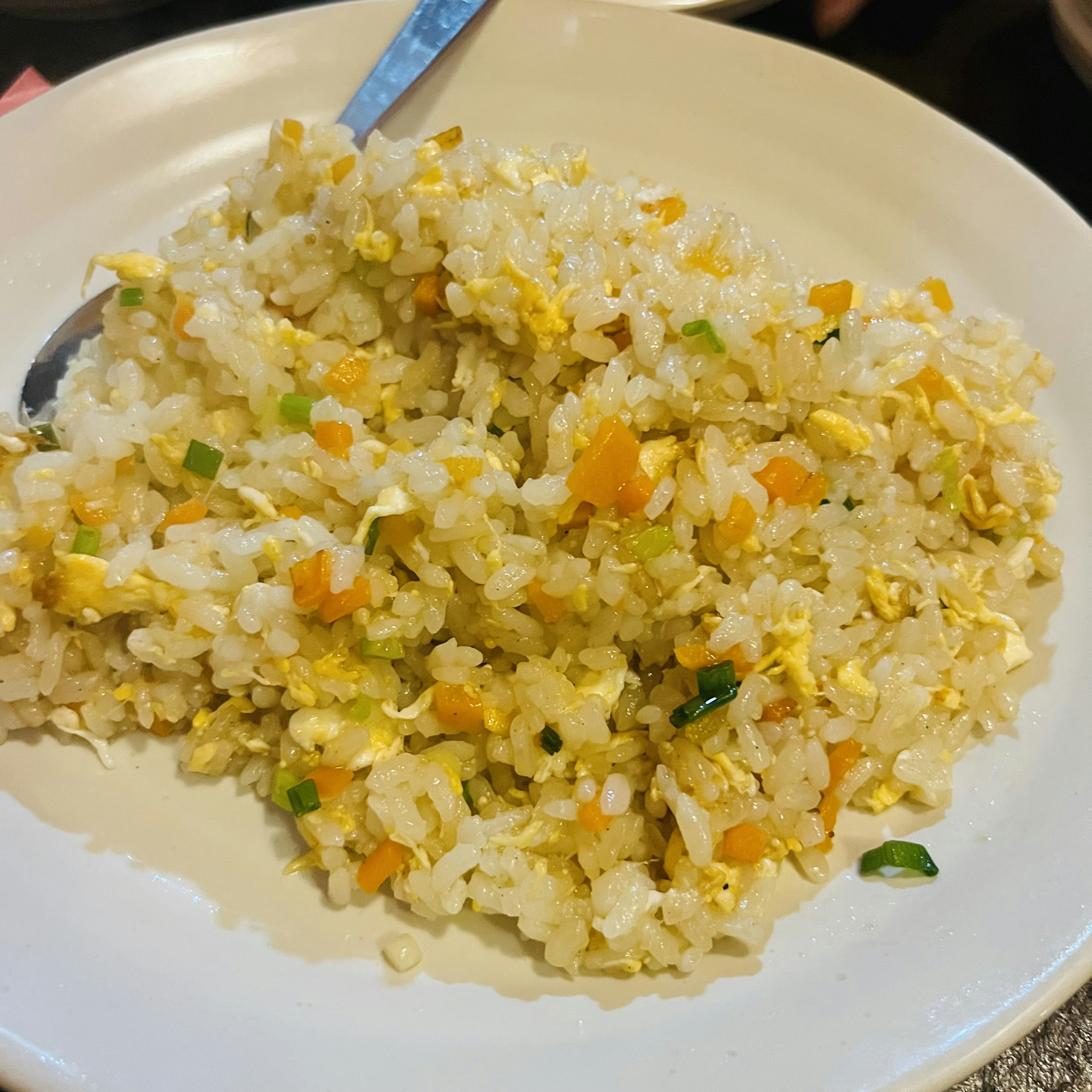 Plate of golden fried rice with green onions and shredded carrots