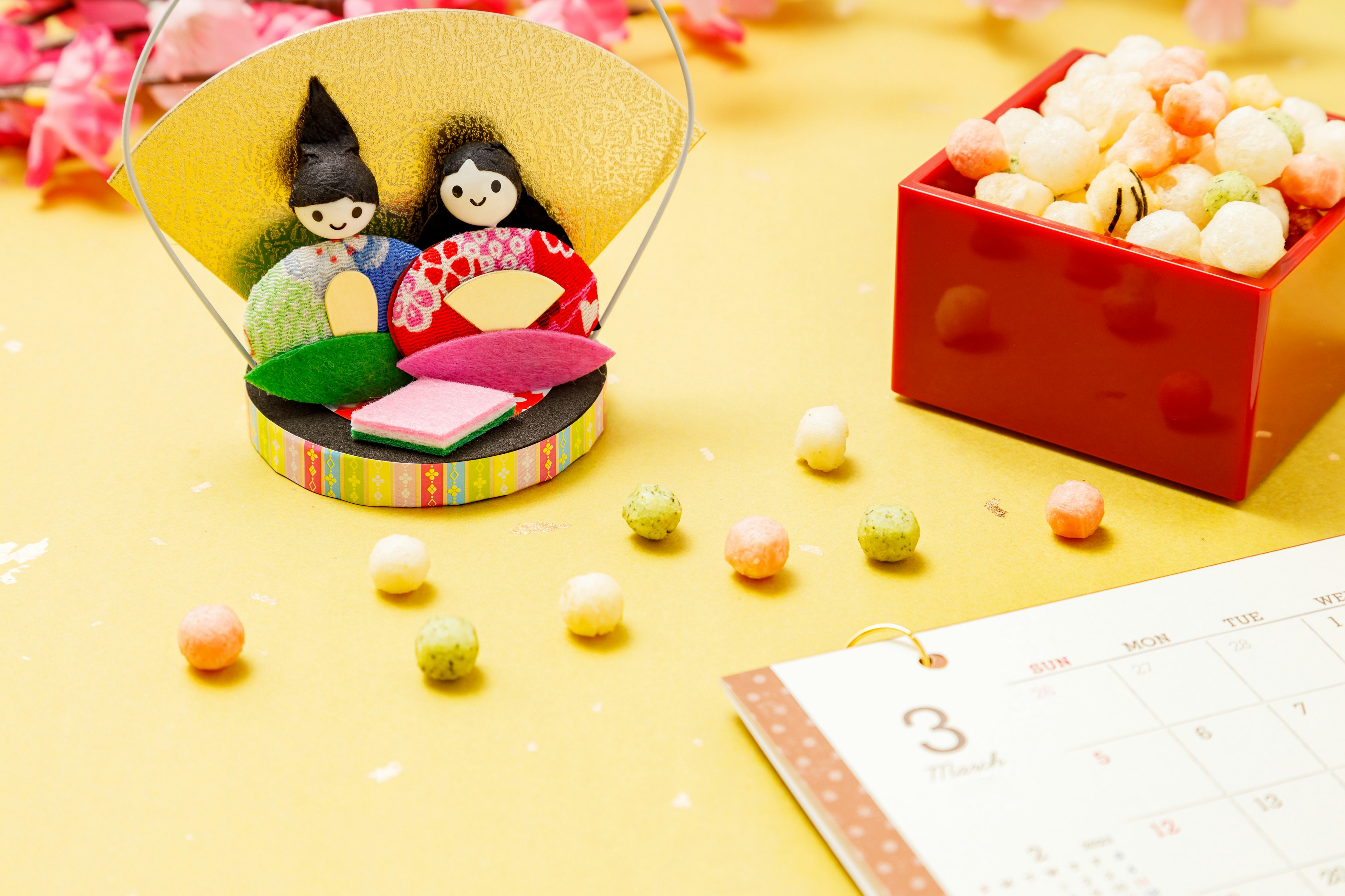 Hinamatsuri decorations with colorful Japanese sweets on a spring-themed background