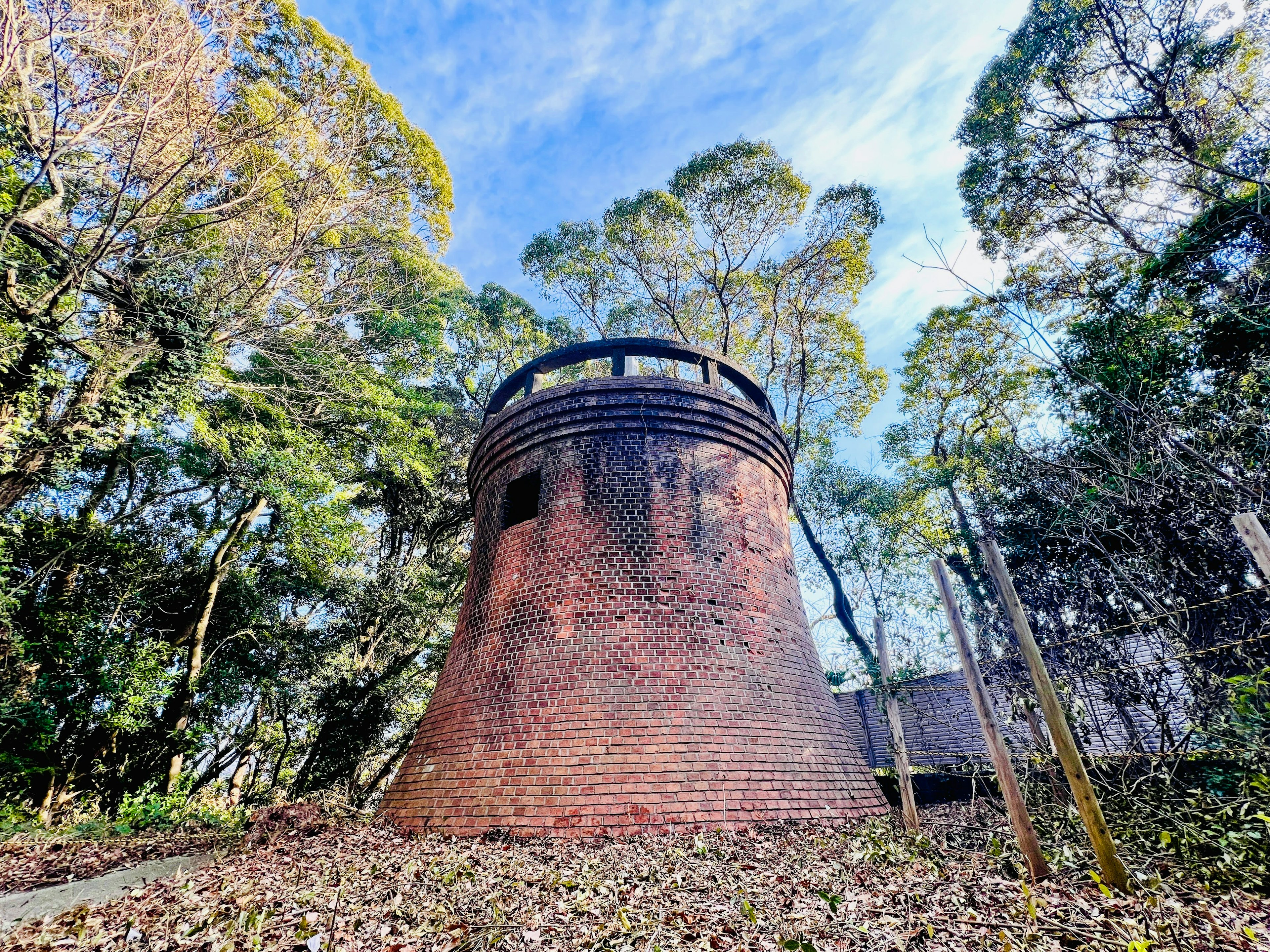 Alter Backsteinturm umgeben von Bäumen und Laub