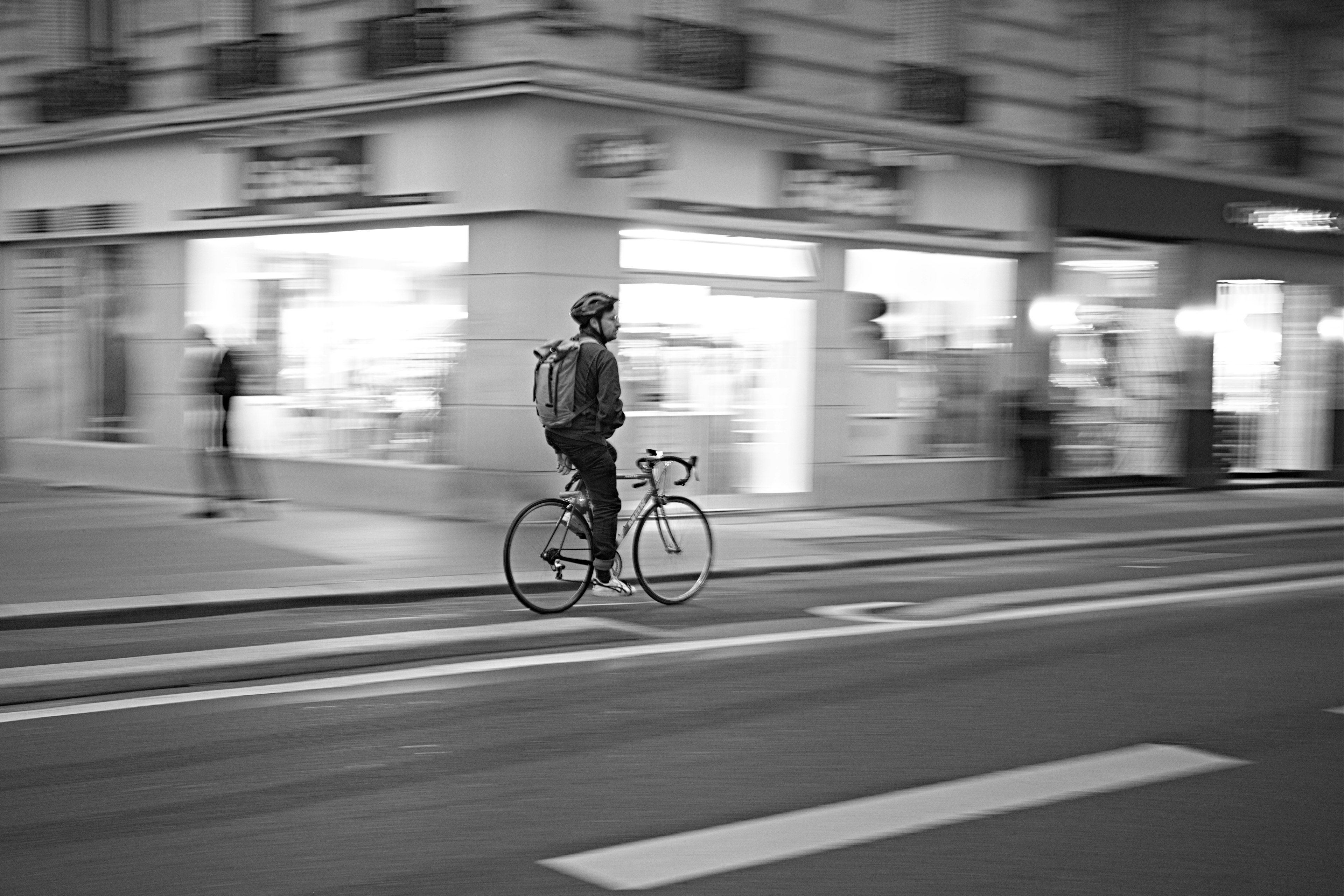 Black and white image of a delivery person riding a bicycle in the city