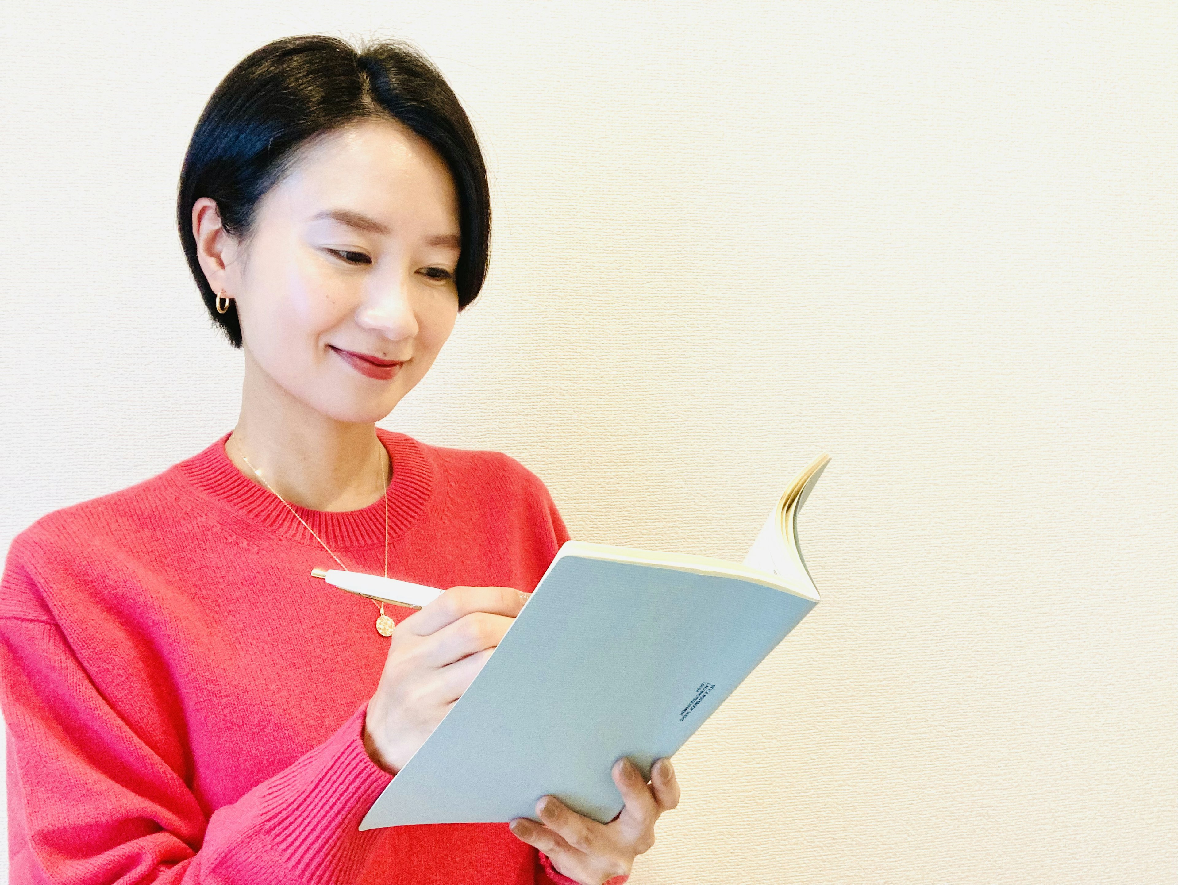 Woman writing in a notebook wearing a bright pink sweater