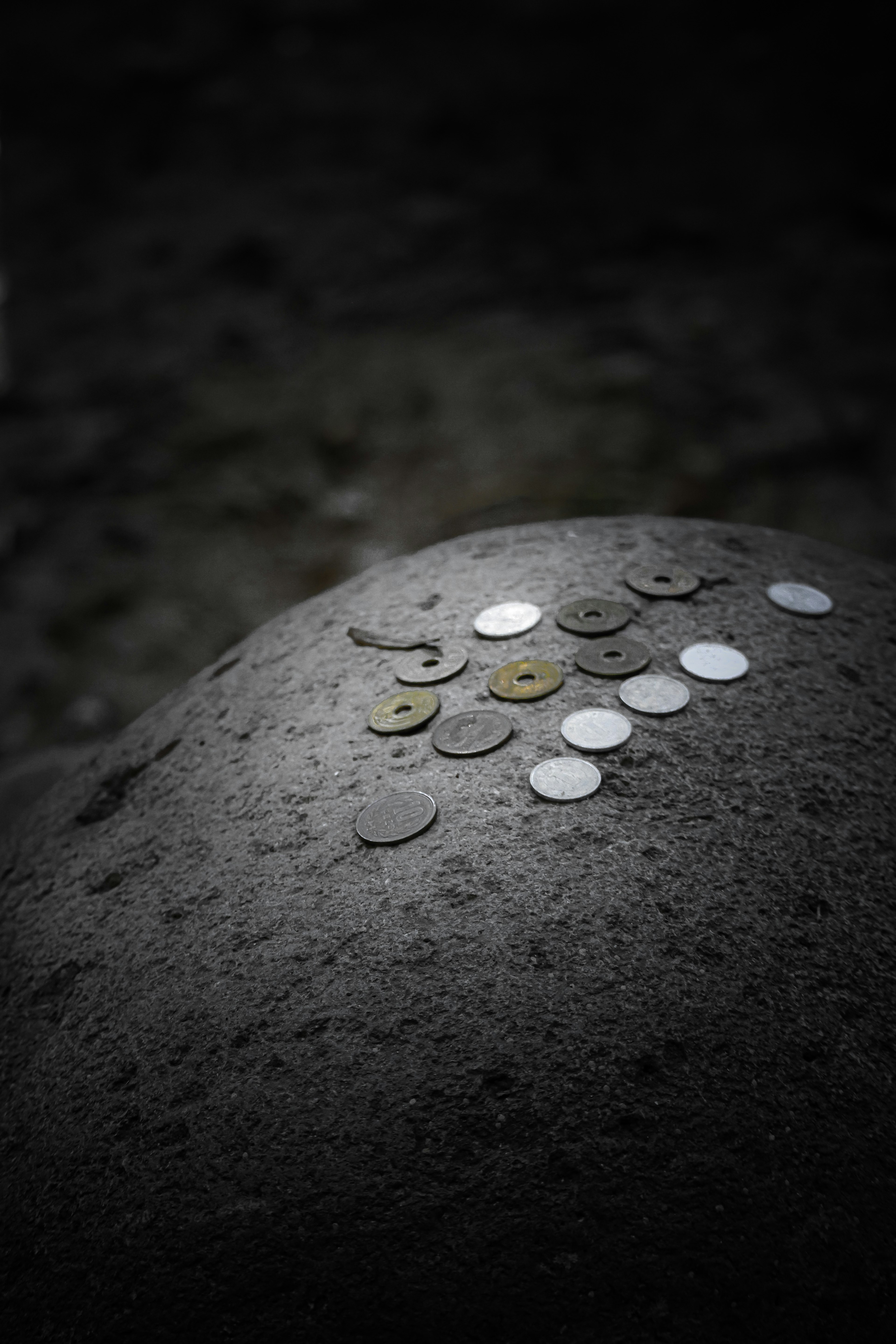 Varias monedas colocadas sobre una roca con un fondo oscuro