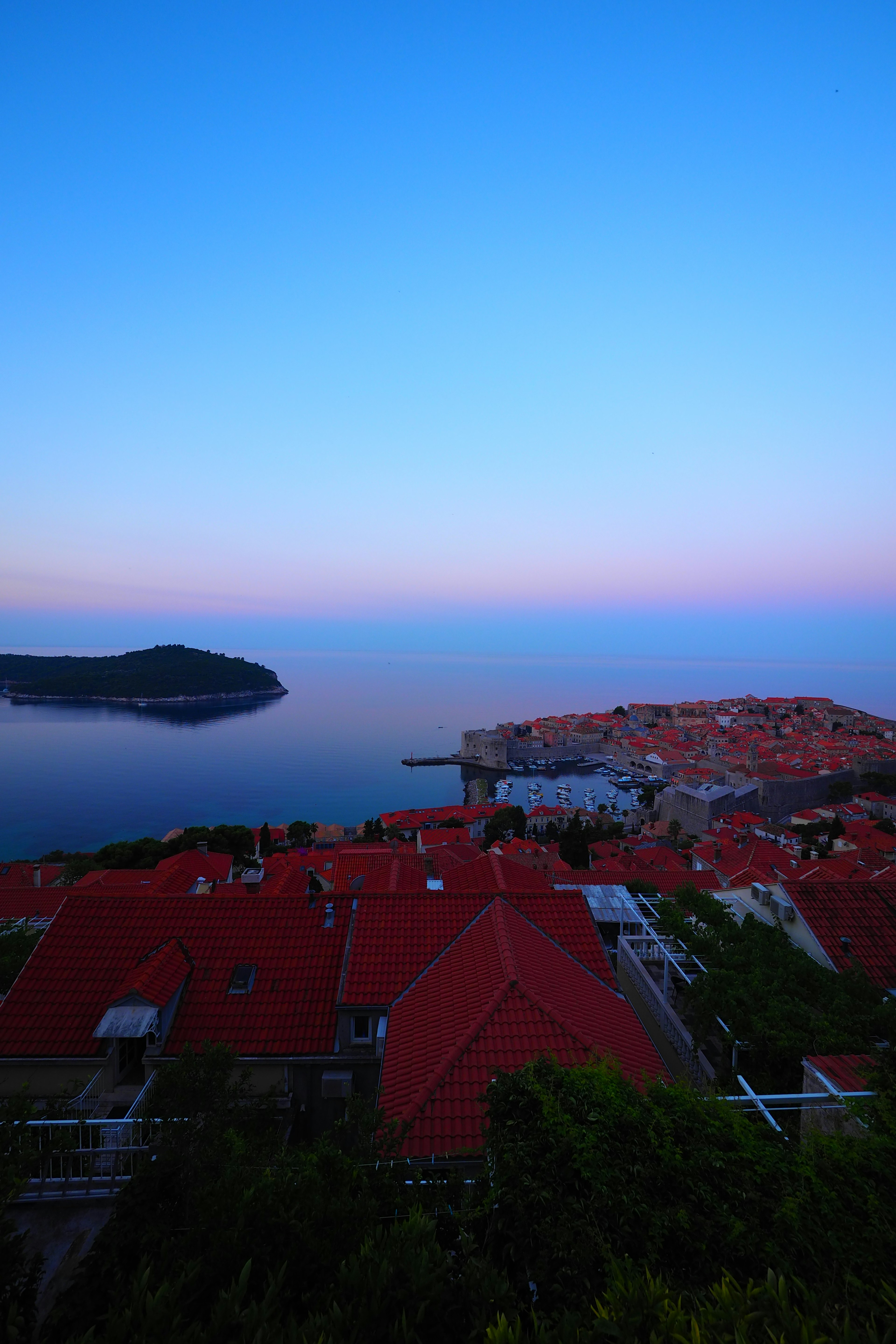 Una vista pintoresca de casas de techos rojos contra un cielo azul y un mar tranquilo