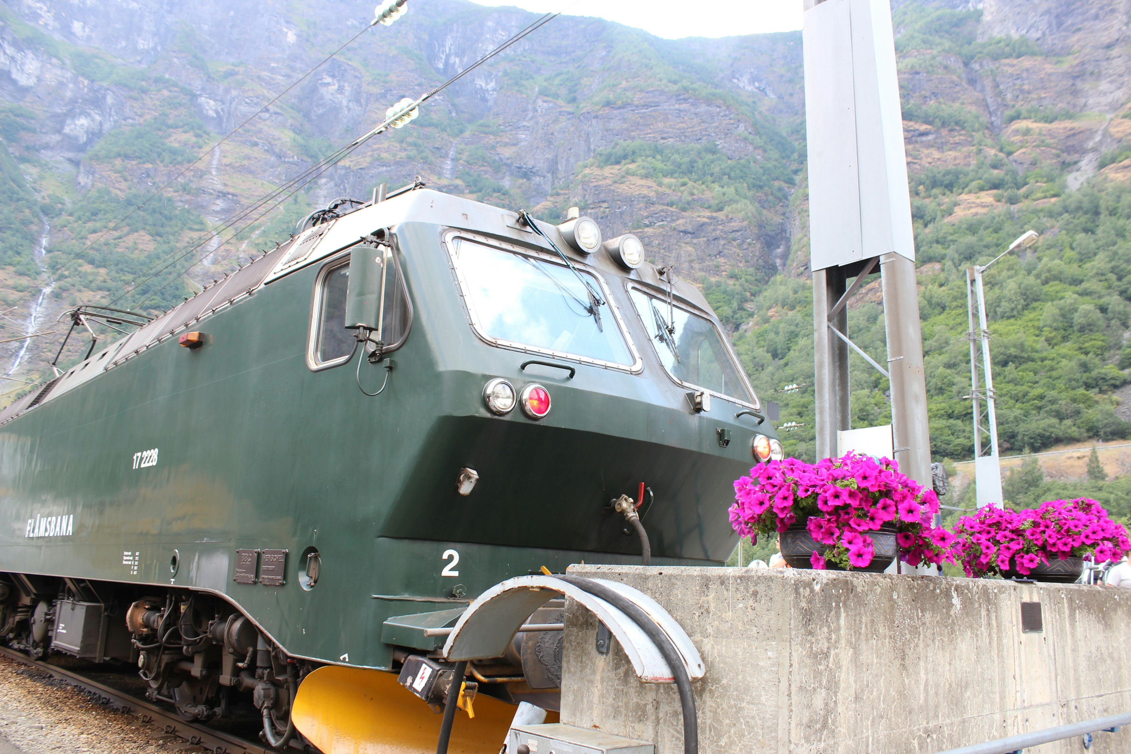 Locomotora verde estacionada en una plataforma decorada con flores