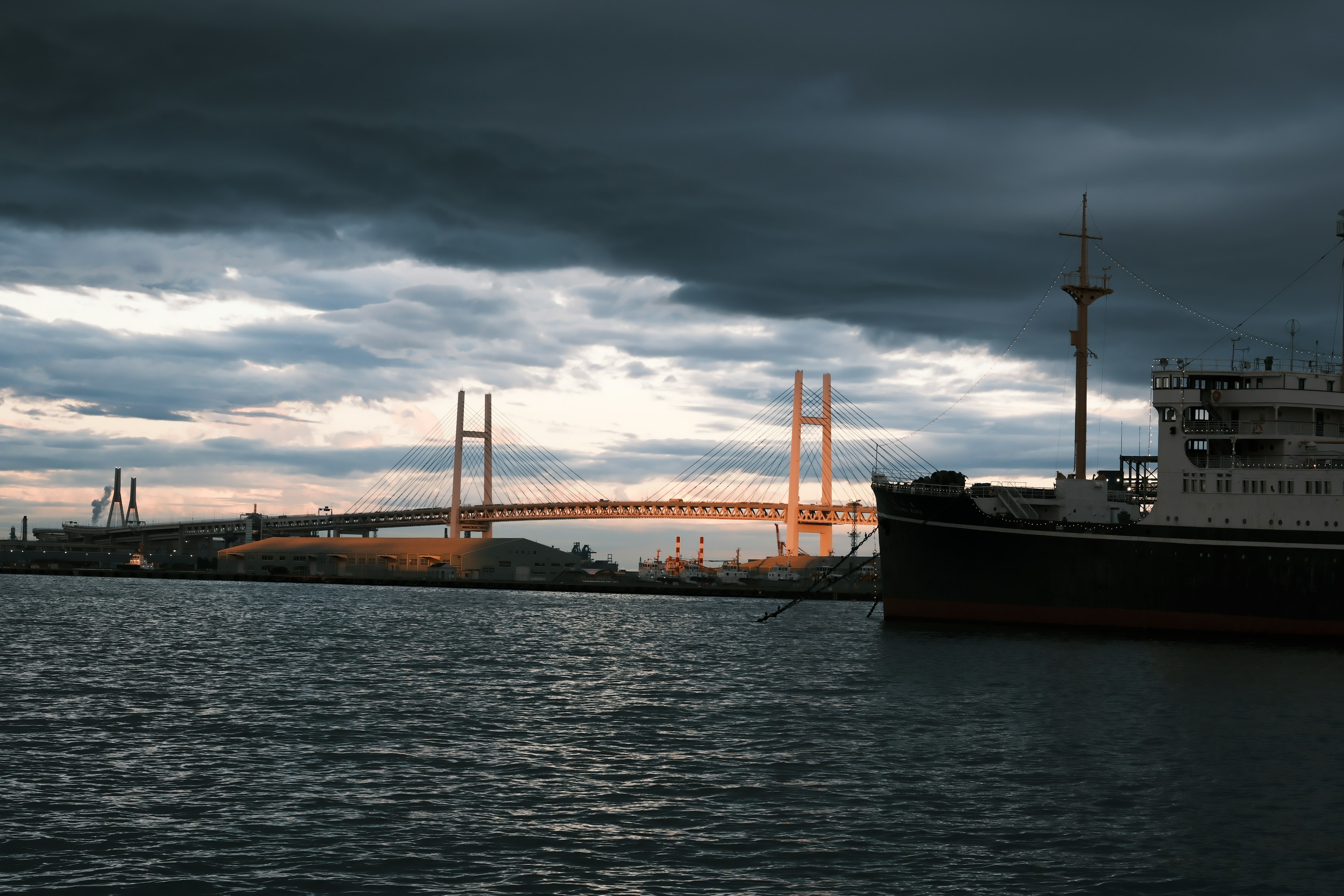 Blick auf ein Schiff und eine Brücke im Hafen von Yokohama unter einem bewölkten Himmel