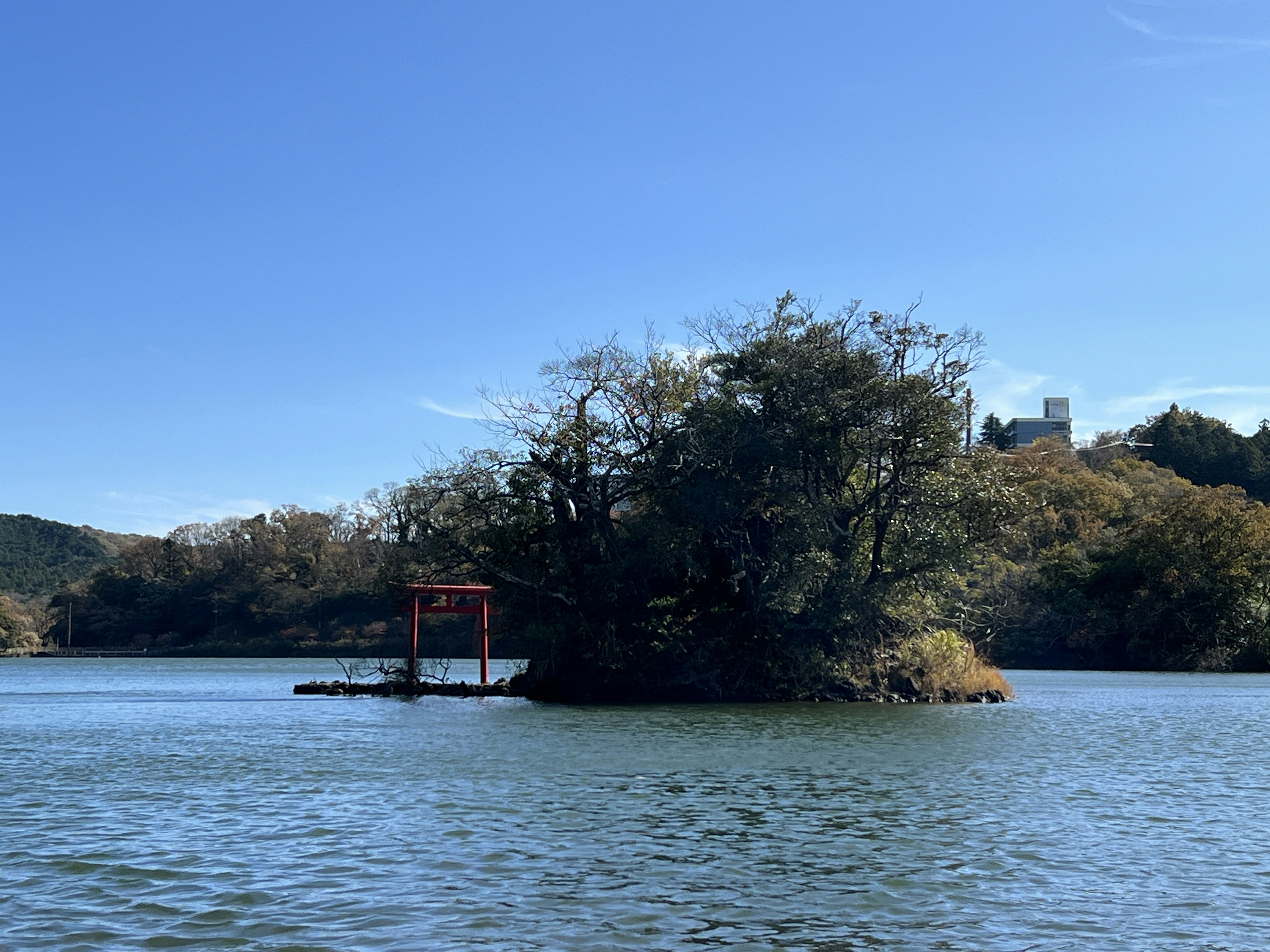 Sebuah pulau kecil dengan gerbang torii merah di bawah langit biru cerah