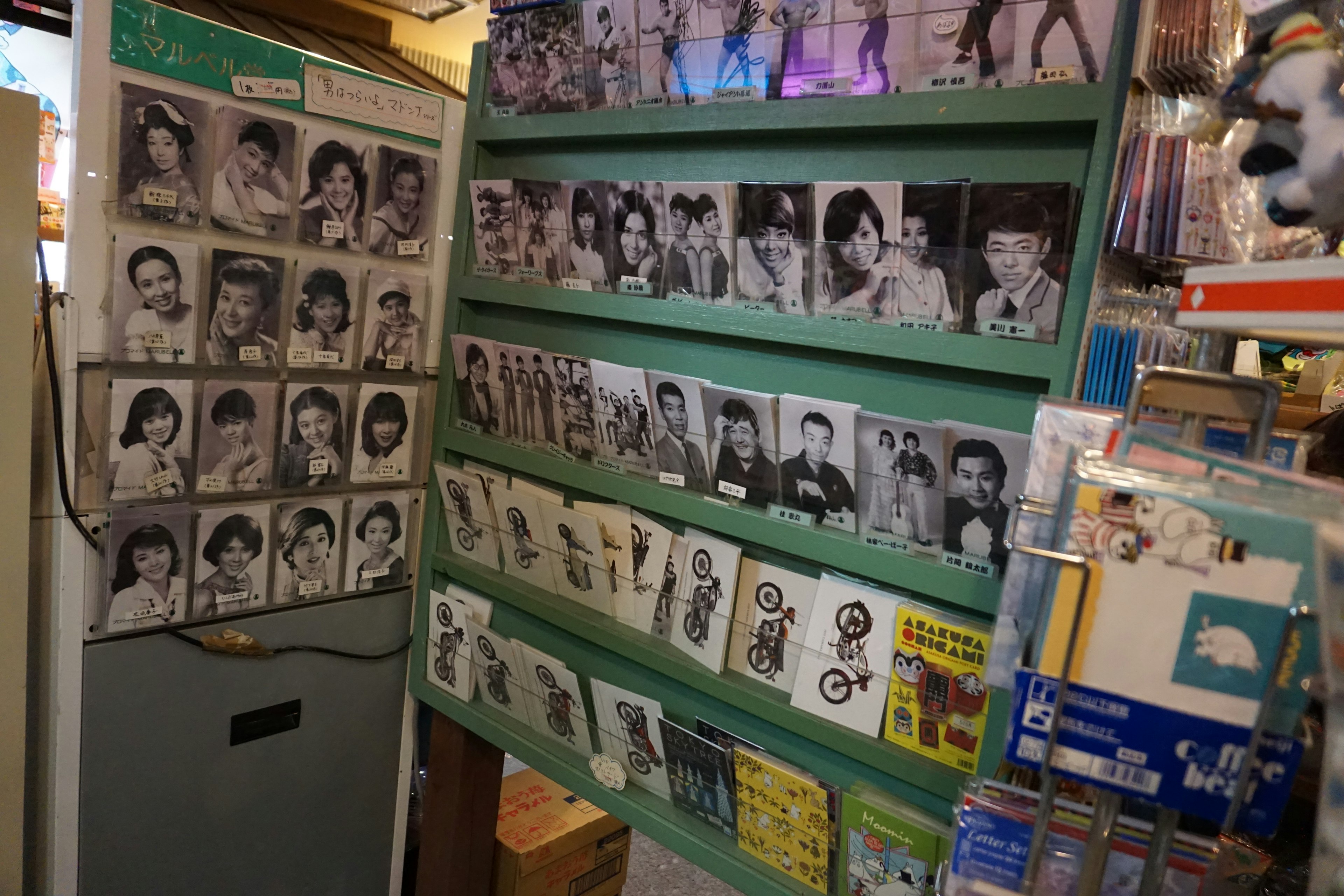 写真が並んだ緑の棚と白黒の肖像写真がある店内の一部